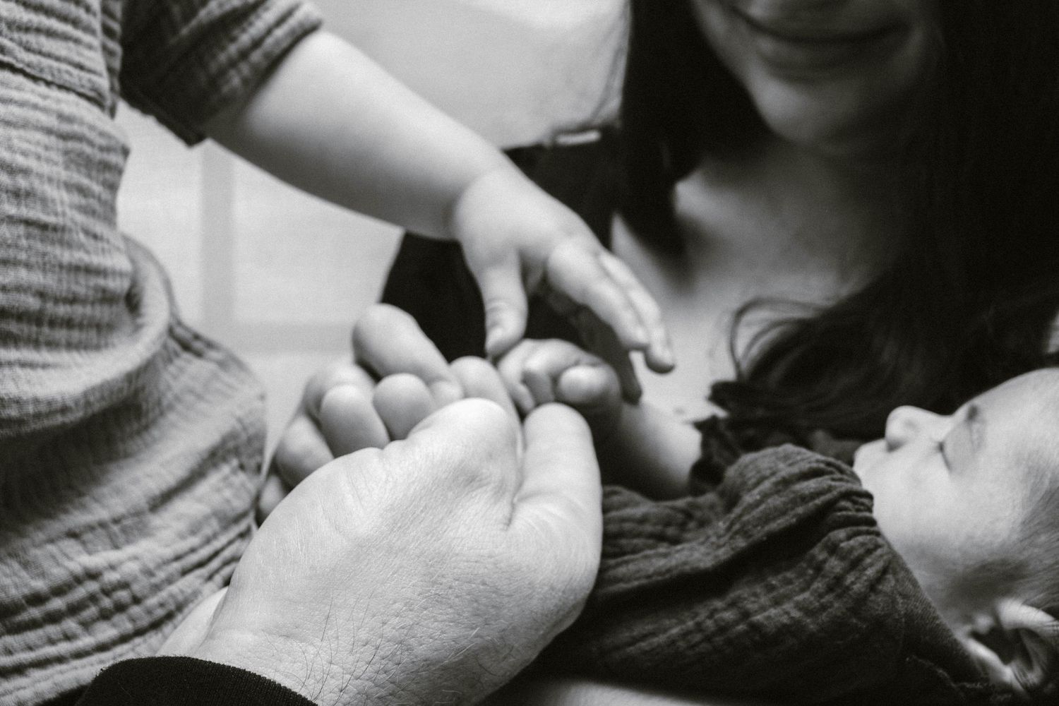 Black and white image of hands tenderly touching in an intimate moment.