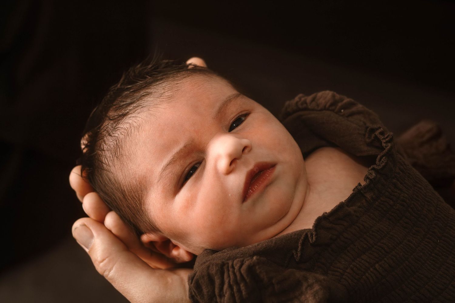 Close-up portrait of a peaceful newborn baby with glowing warm lighting.