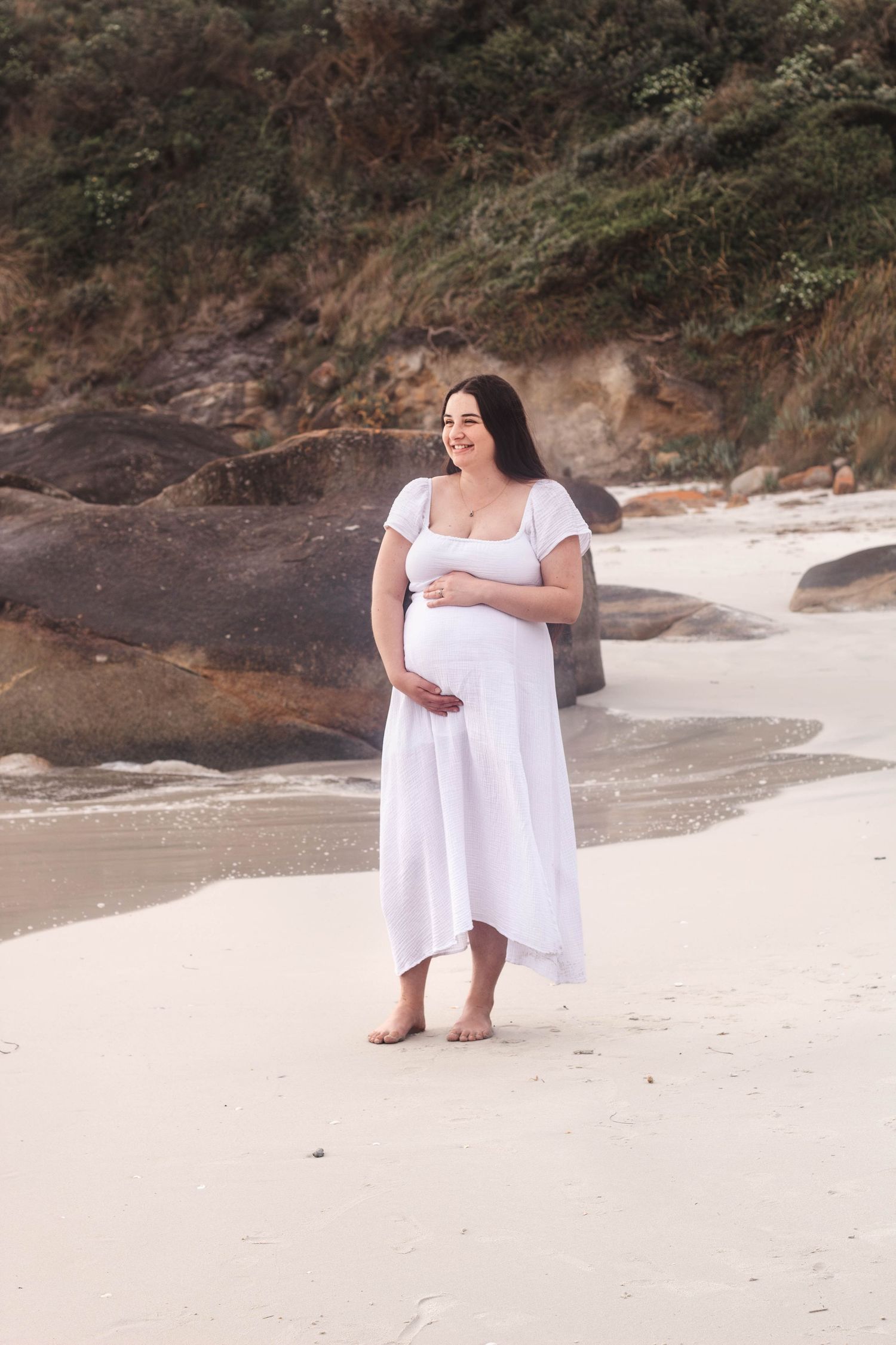 Natural light beach photography session featuring coastal rocks and sandy shoreline.