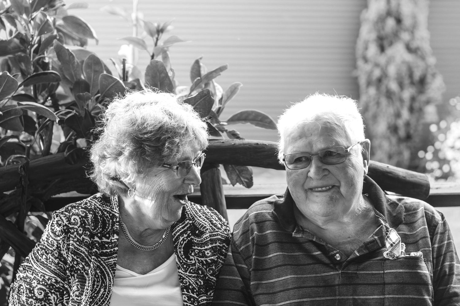 Senior couple in casual wear sharing a relaxed moment outdoors in black and white.