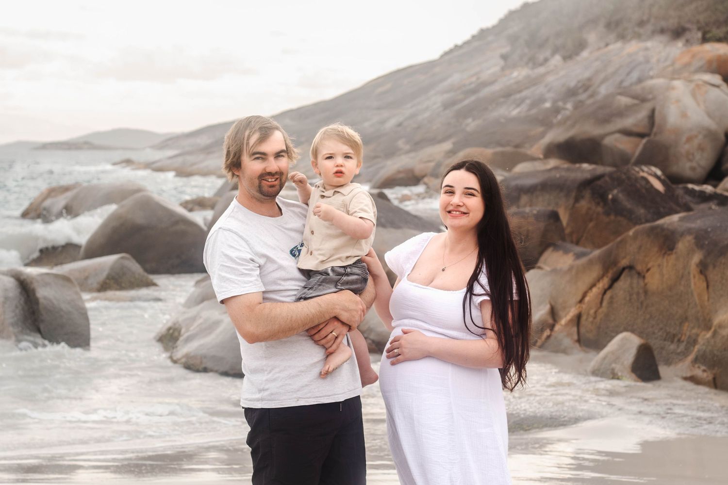 Family portrait on a beautiful rocky coastline beach during golden hour.