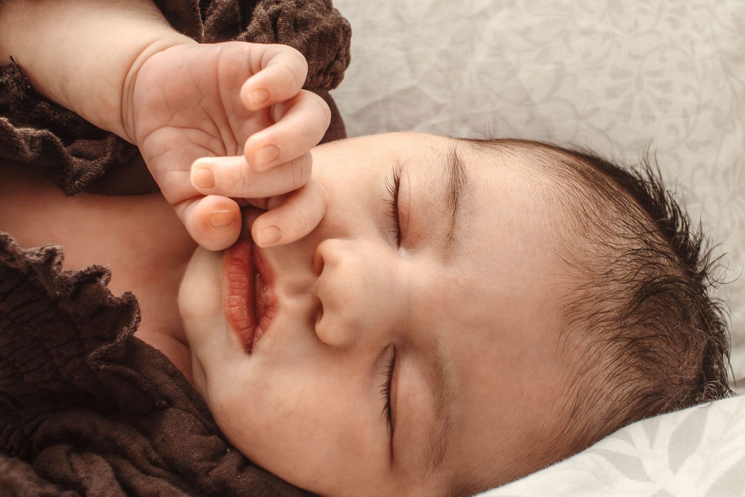 Peaceful sleeping portrait in soft lighting with brown textured clothing.