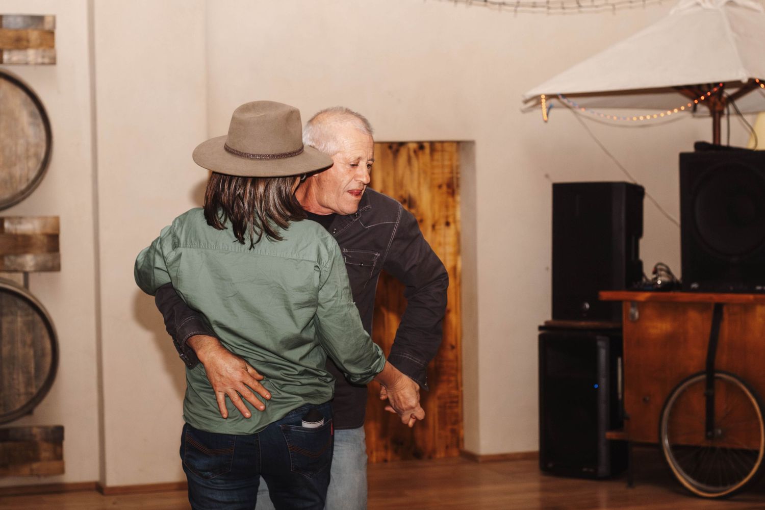 Two people dancing together in a rustic room with wooden barrels in the background.