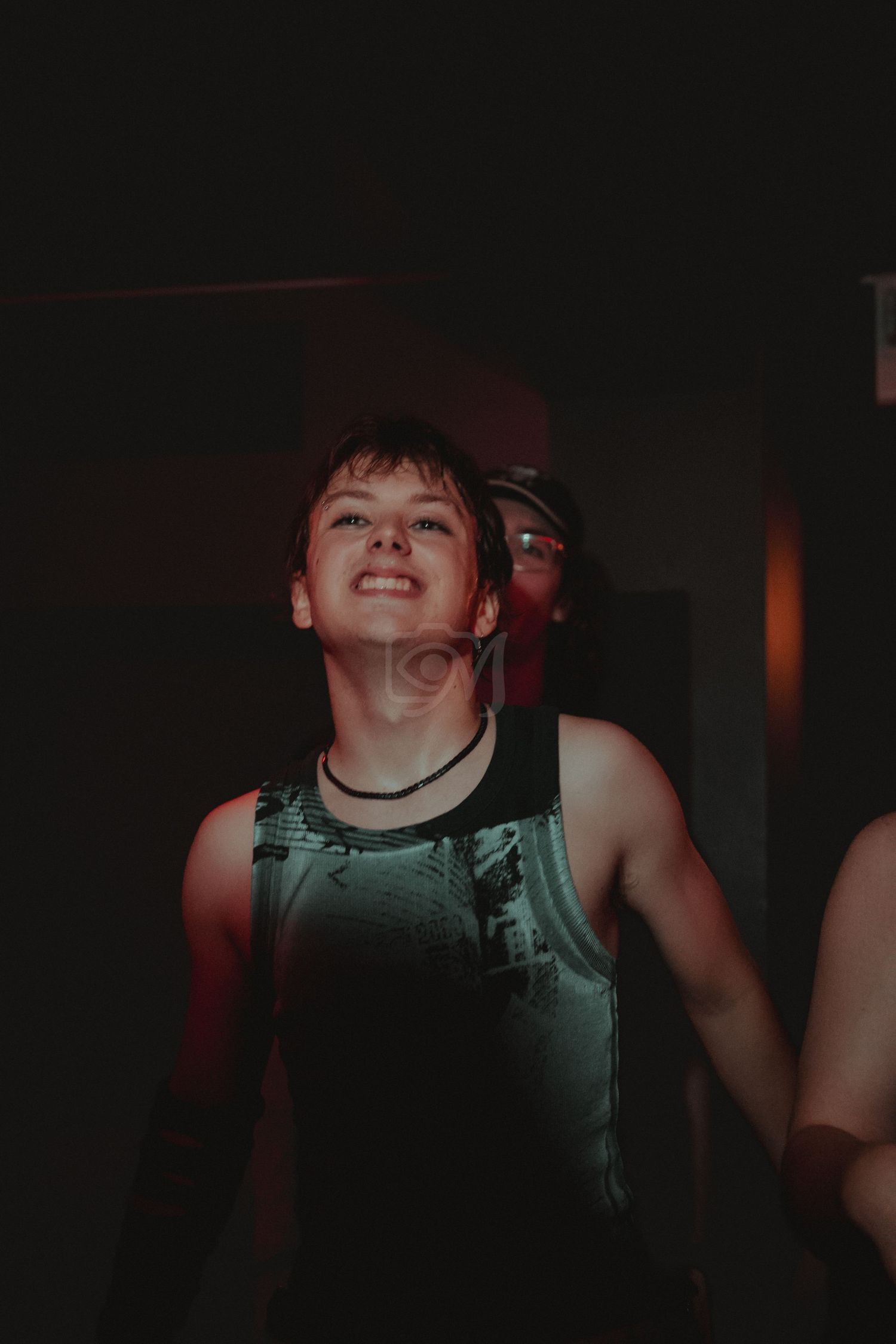 Person dancing joyfully in a dimly lit nightclub environment.