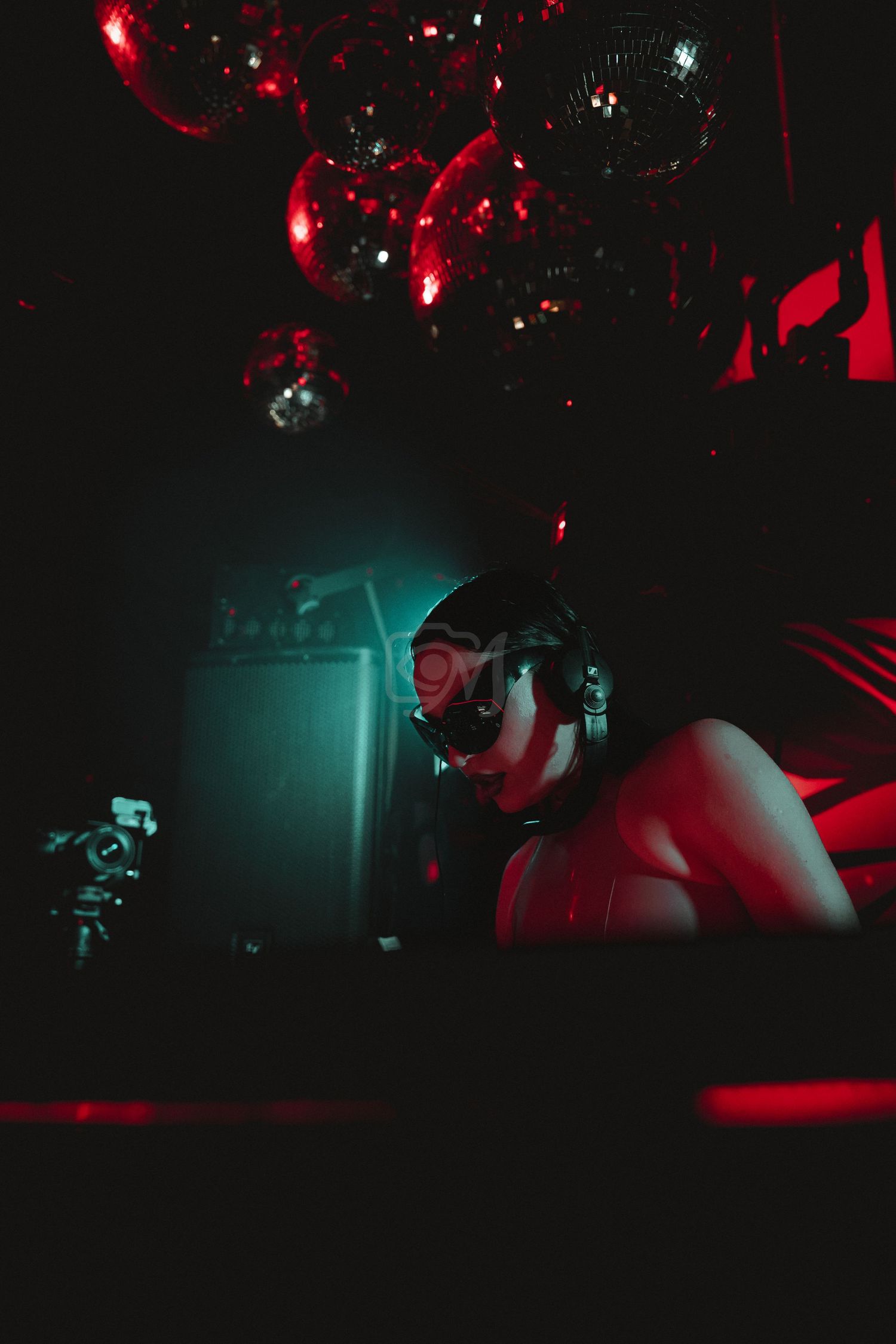 Club scene with disco balls casting red reflections and teal accent lighting.