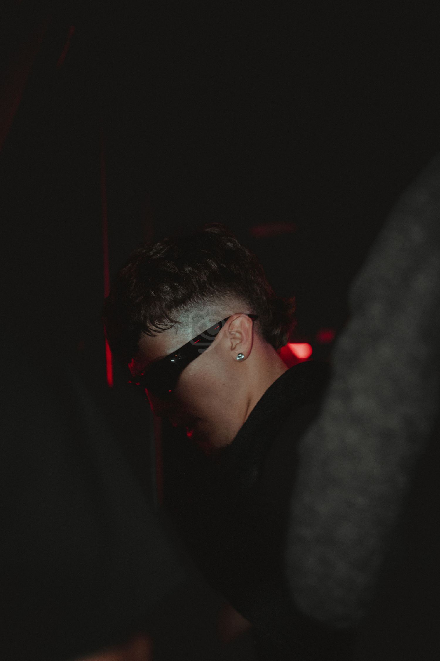 Dark moody nightclub portrait with red accent lighting and dramatic shadows.