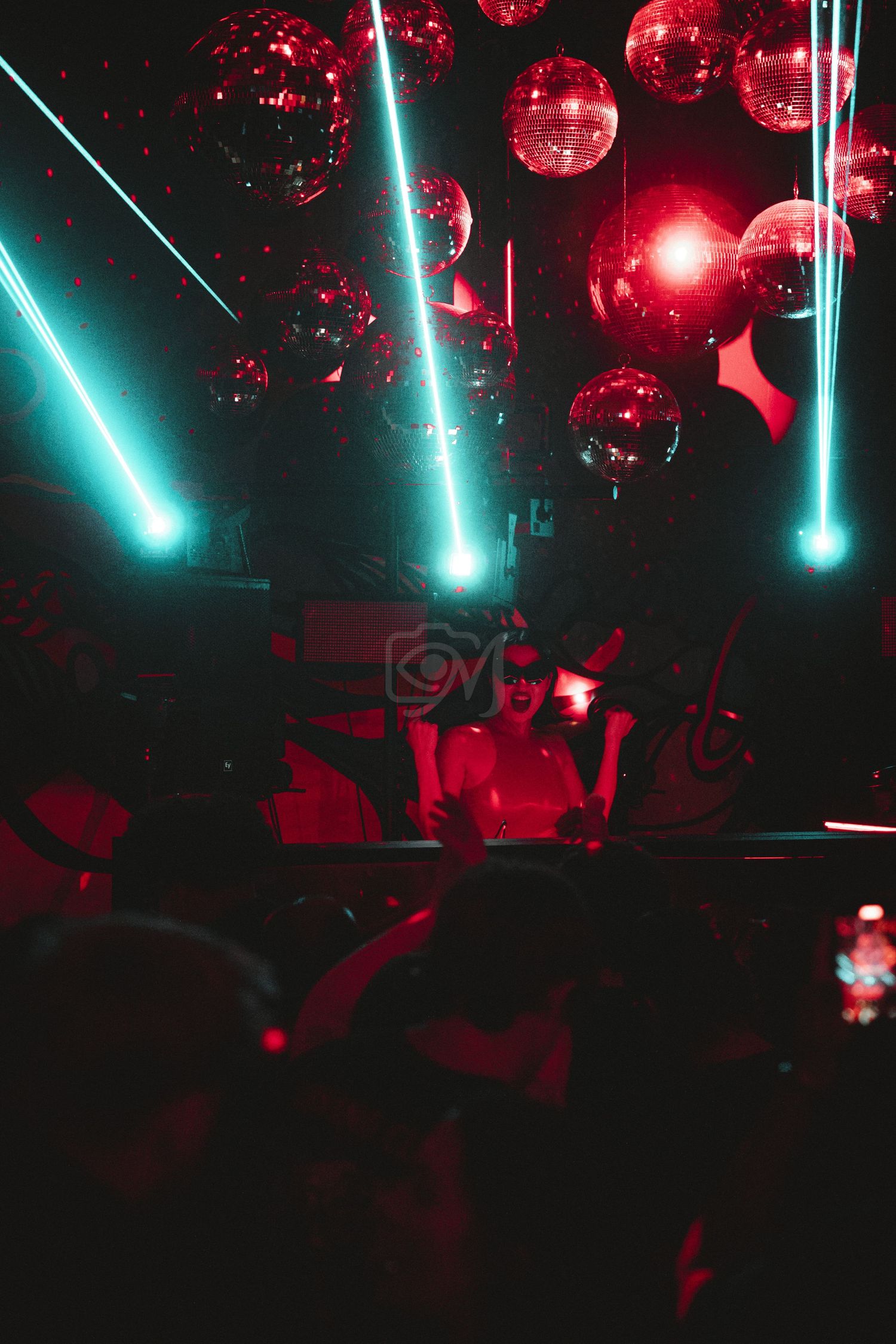 Nightclub interior with disco balls and neon turquoise lighting creating dynamic atmosphere.