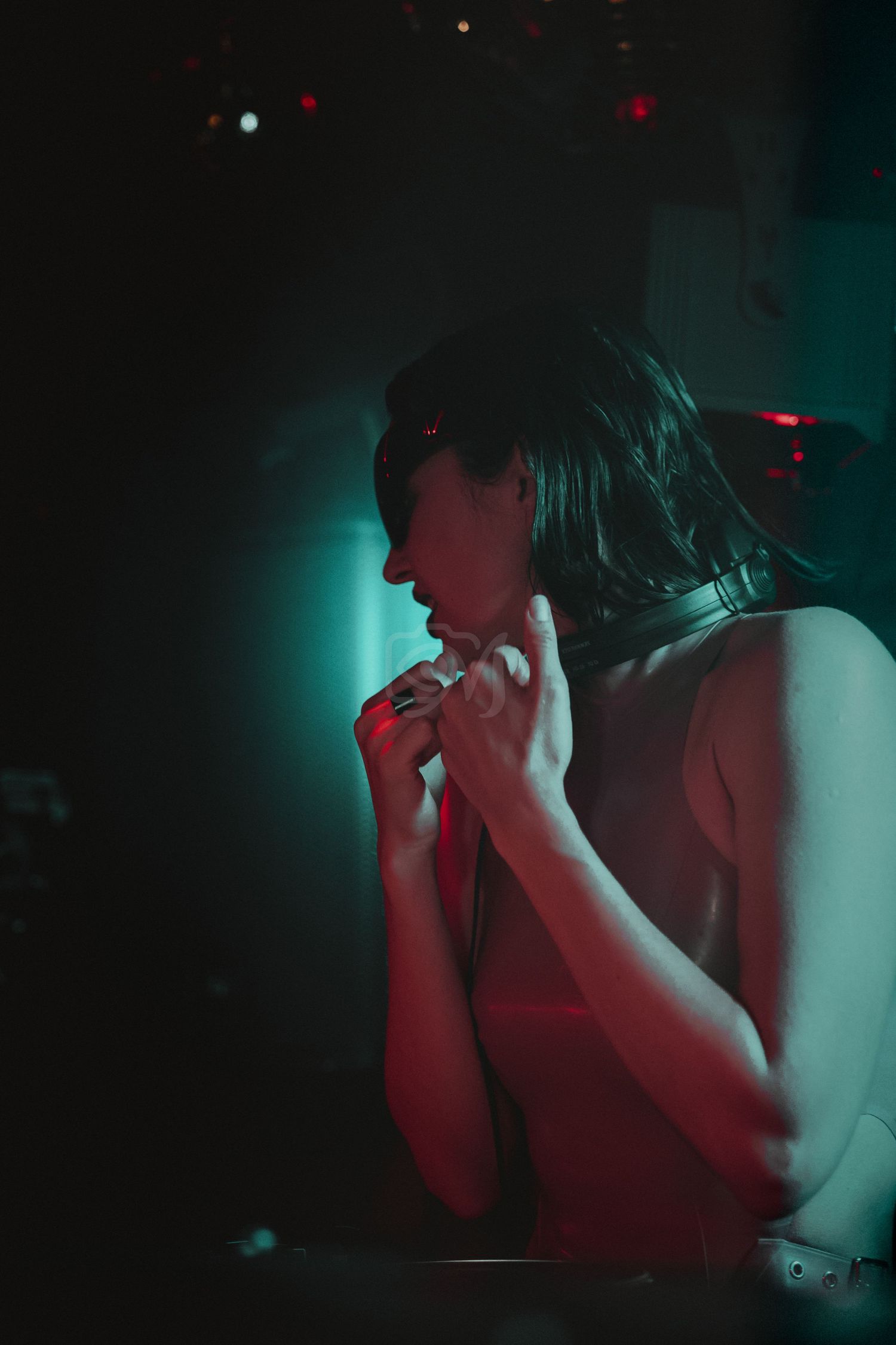 Figure silhouetted against turquoise and red club lighting in dramatic pose.