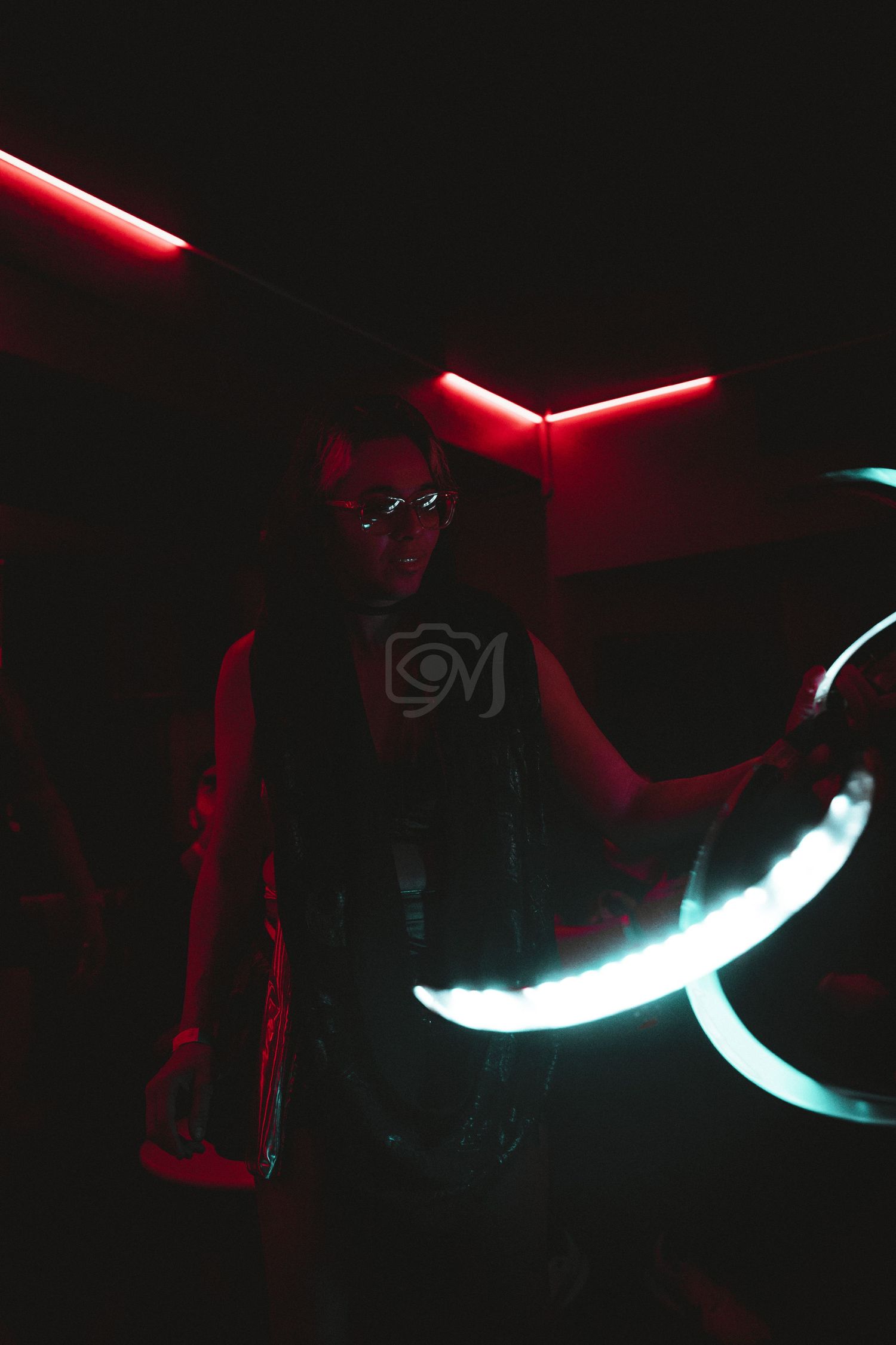 Silhouetted figure against neon red and blue lighting in nightclub setting.