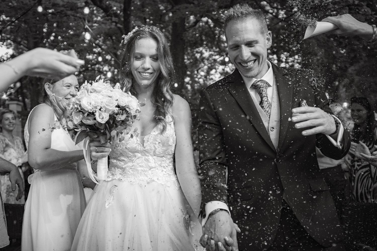 Black and white outdoor wedding photo with floral bouquet details.