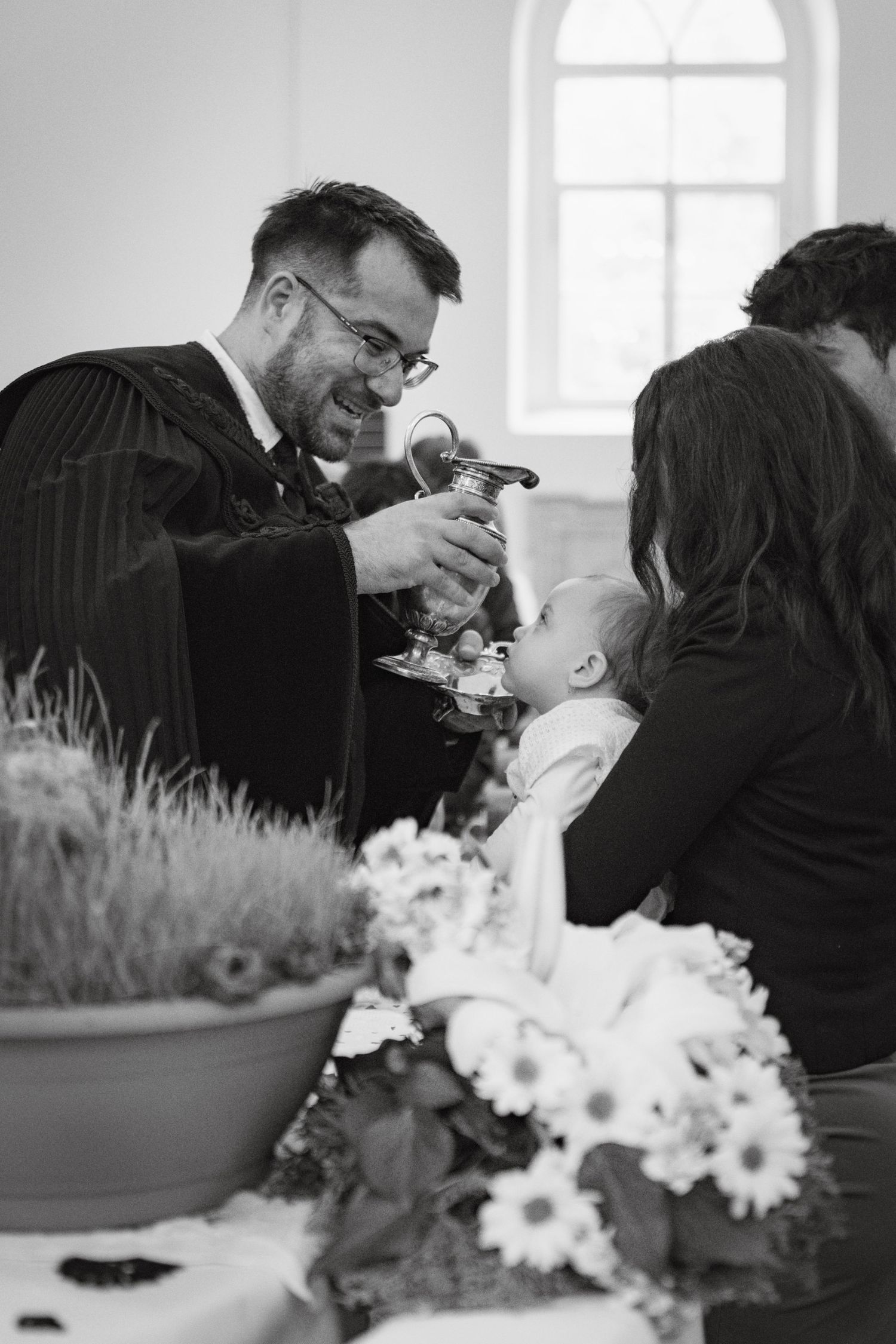 Black and white romantic moment captured with floral arrangements in foreground.