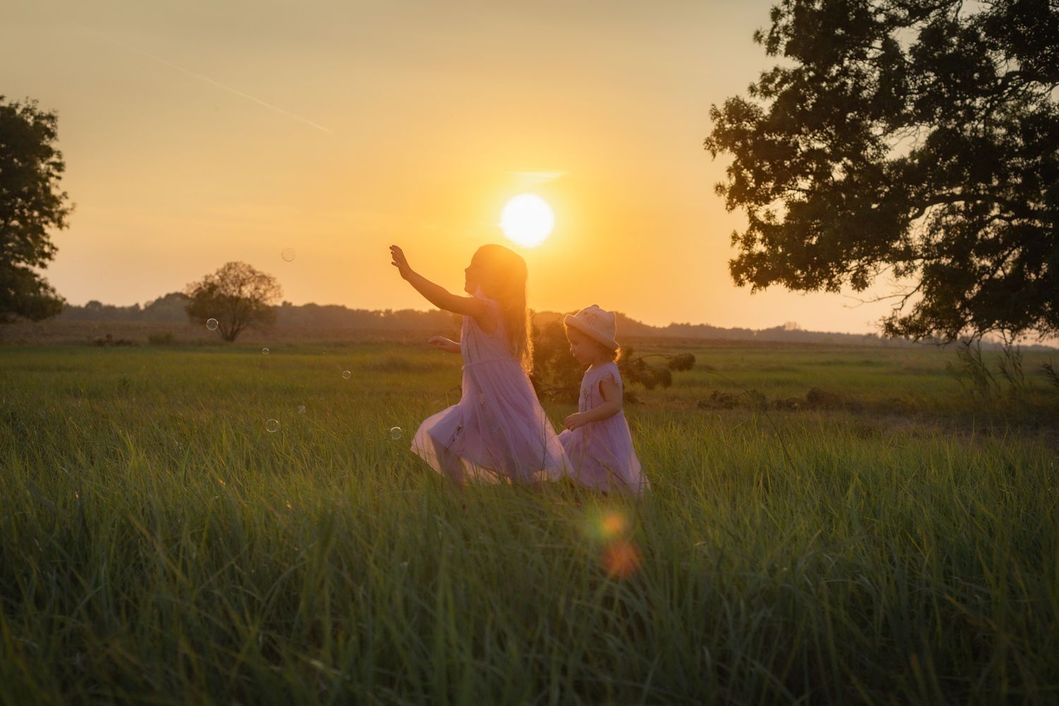 Two silhouettes dancing in a field against a golden sunset backdrop.