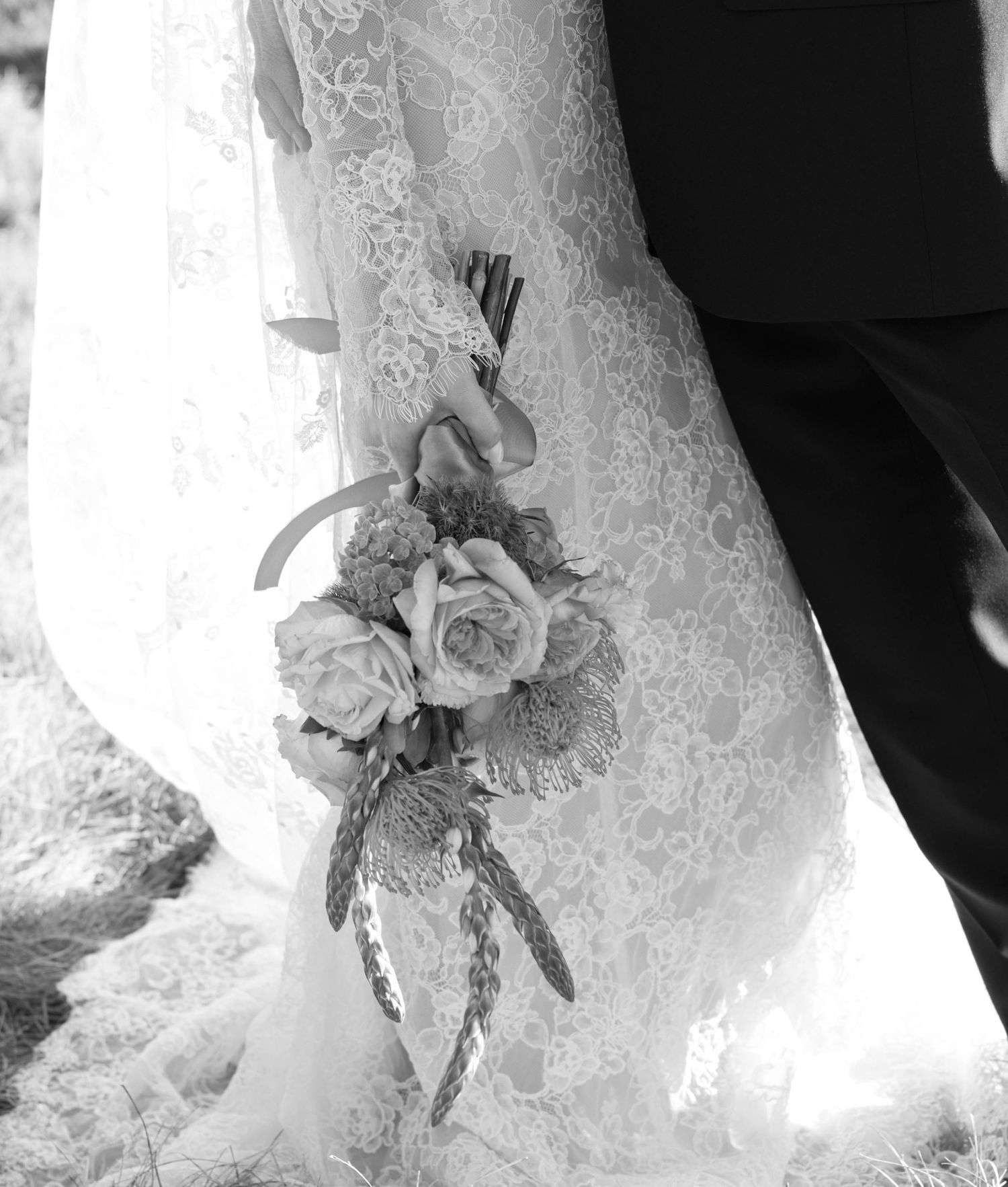 Close-up detail of delicate white lace wedding dress bodice with floral embellishments and intricate beading.
