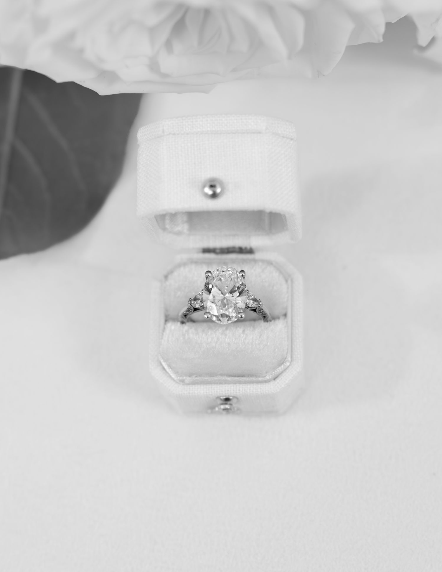 Black and white photo of a diamond engagement ring in an elegant white velvet ring box.
