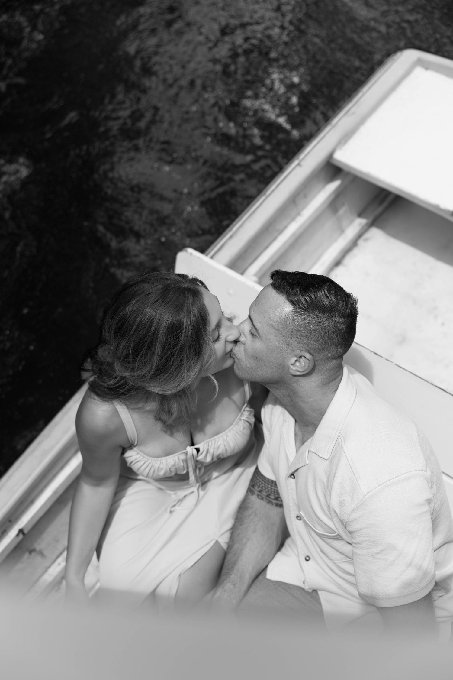 A romantic black and white photo sequence showing a couple sharing a tender kiss while sitting together outdoors.