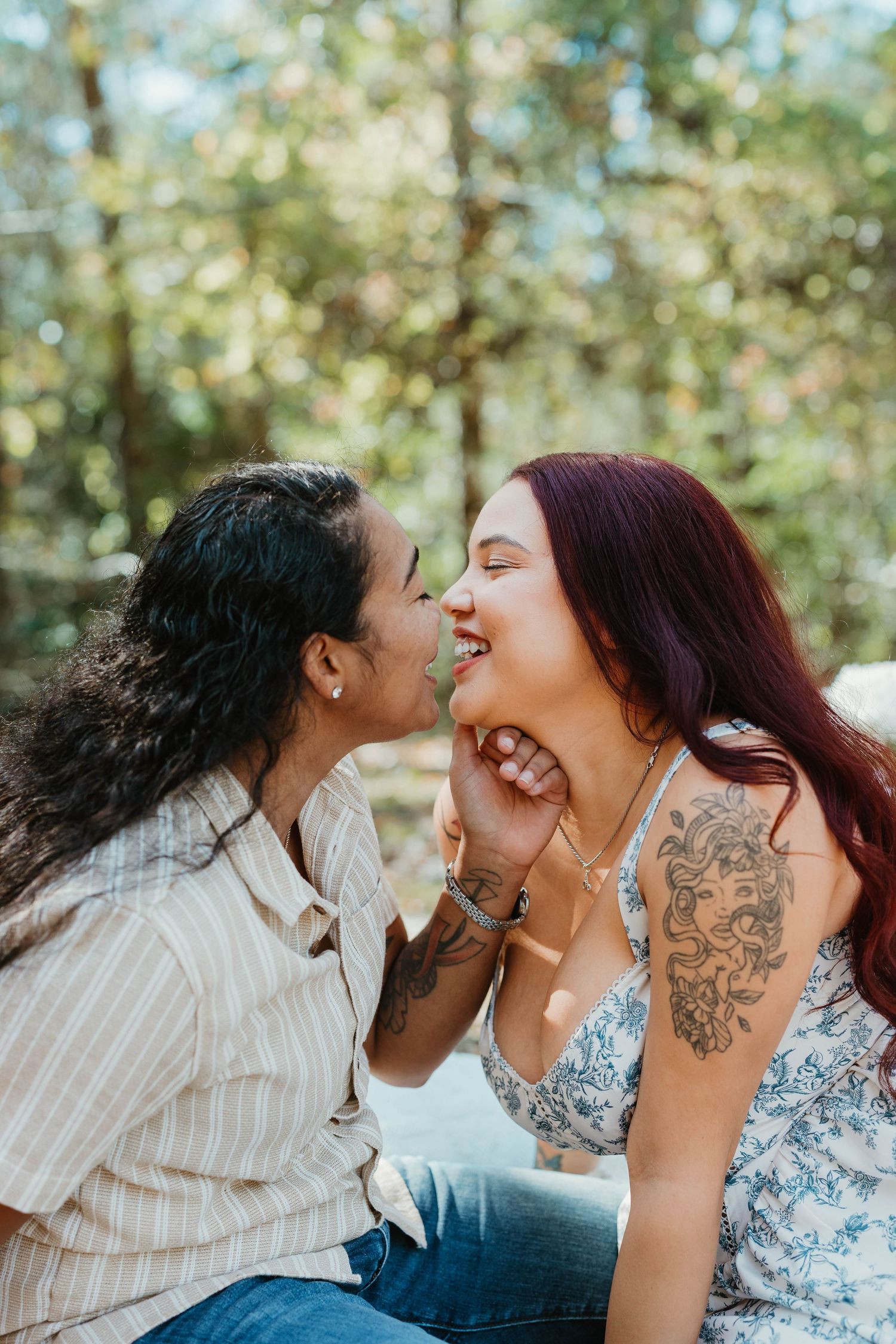 A joyful couple sharing a tender moment outdoors with natural bokeh lighting in the background.