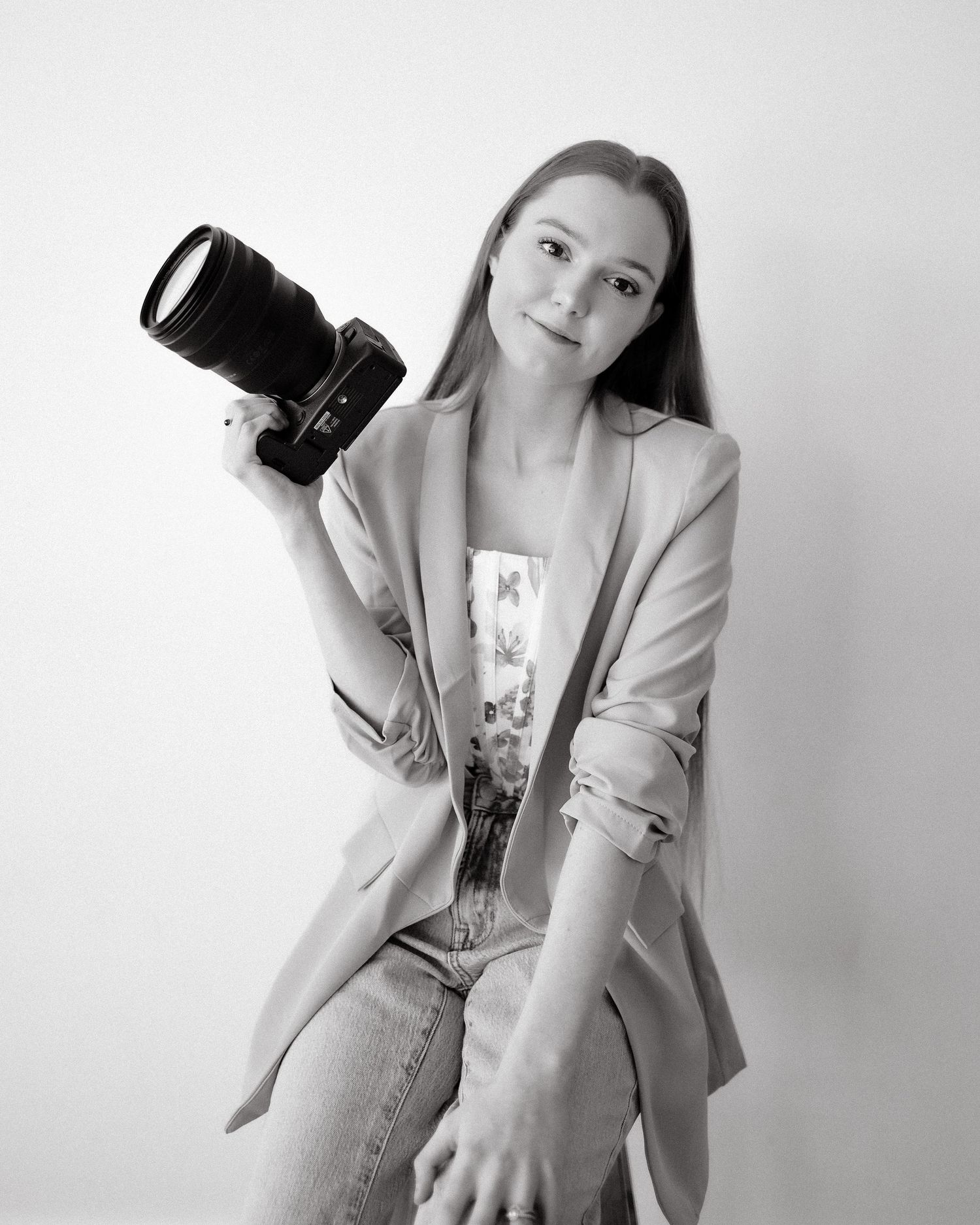 Black and white fashion photo series showing a model in a light blazer holding a camera in various artistic poses.
