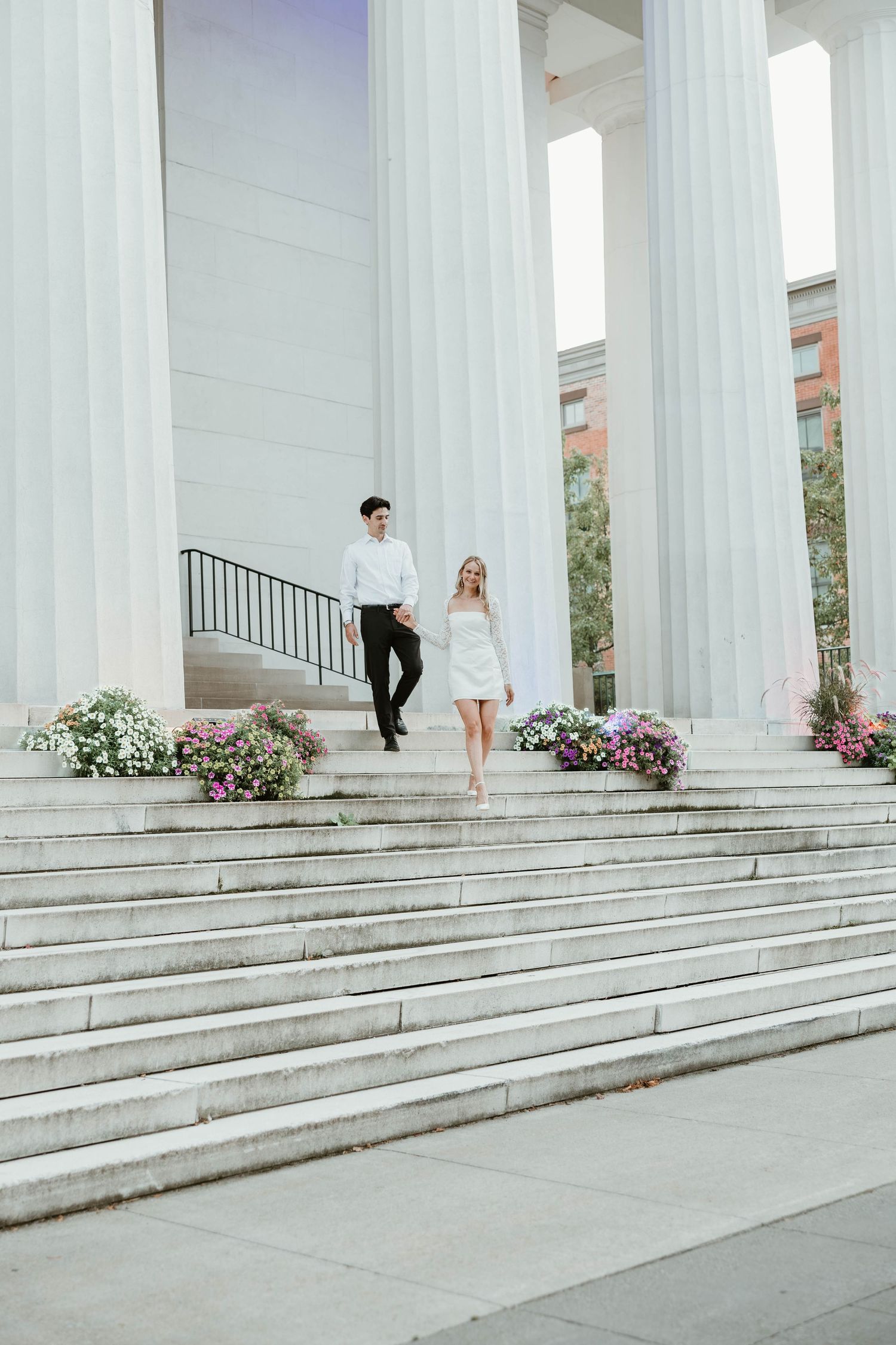 A series of white columns and steps with people walking across them in a classical architectural setting.