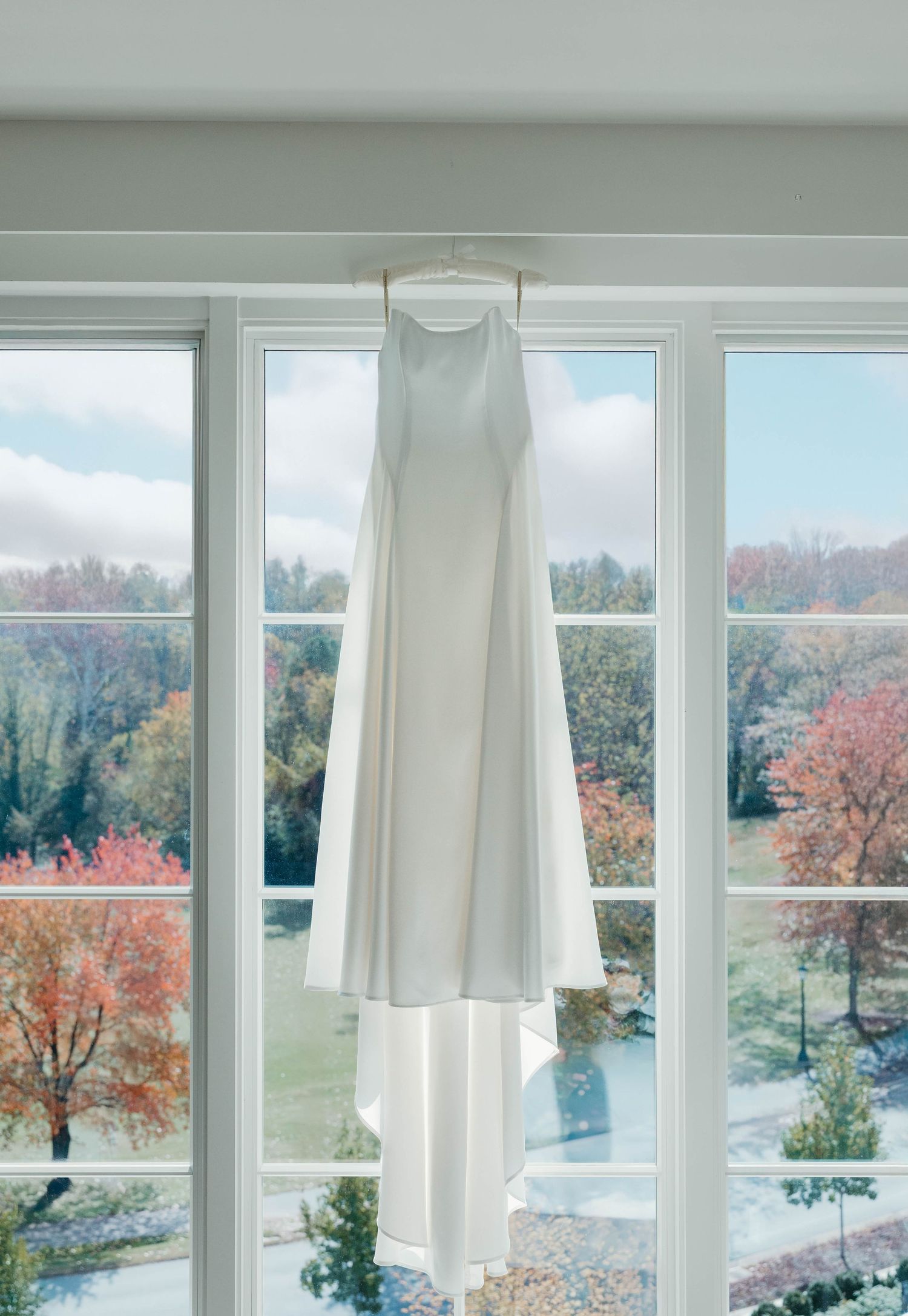 Large windows in a modern home showcase a scenic autumn landscape with colorful trees and a pond outside.