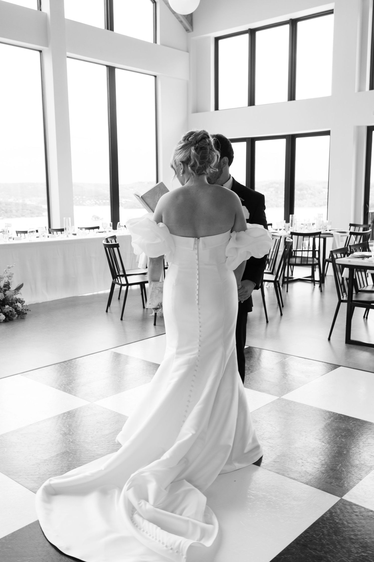 A classic black and white wedding photo in an elegant reception venue with checkerboard floor.