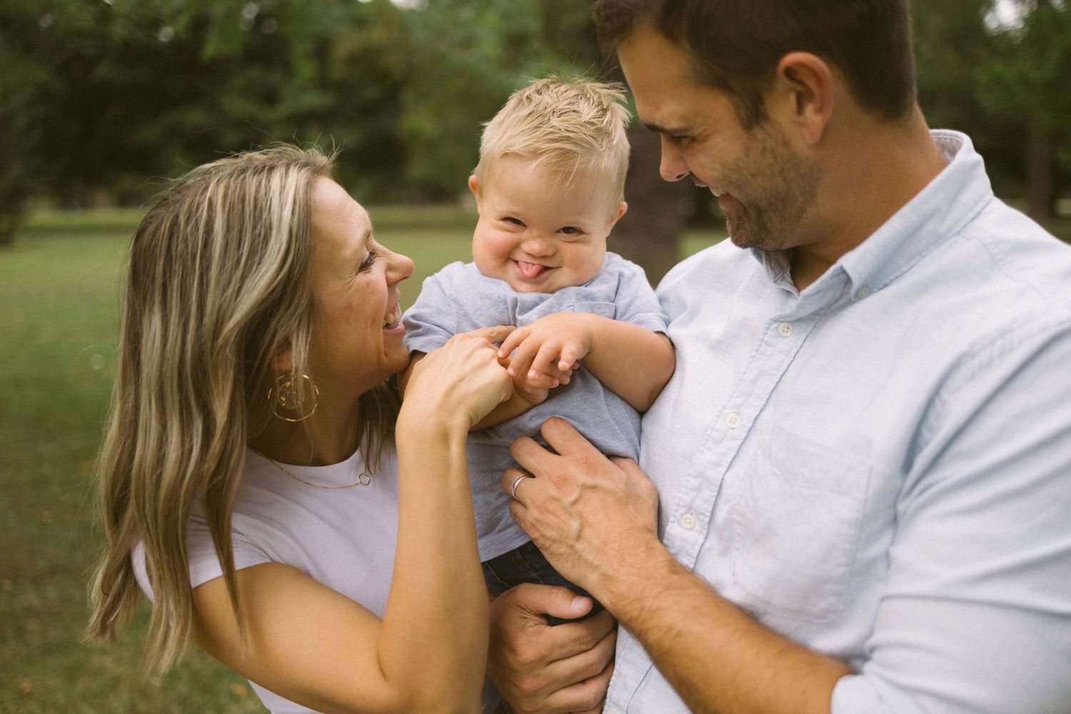 Parents sharing a joyful moment with their baby outdoors.