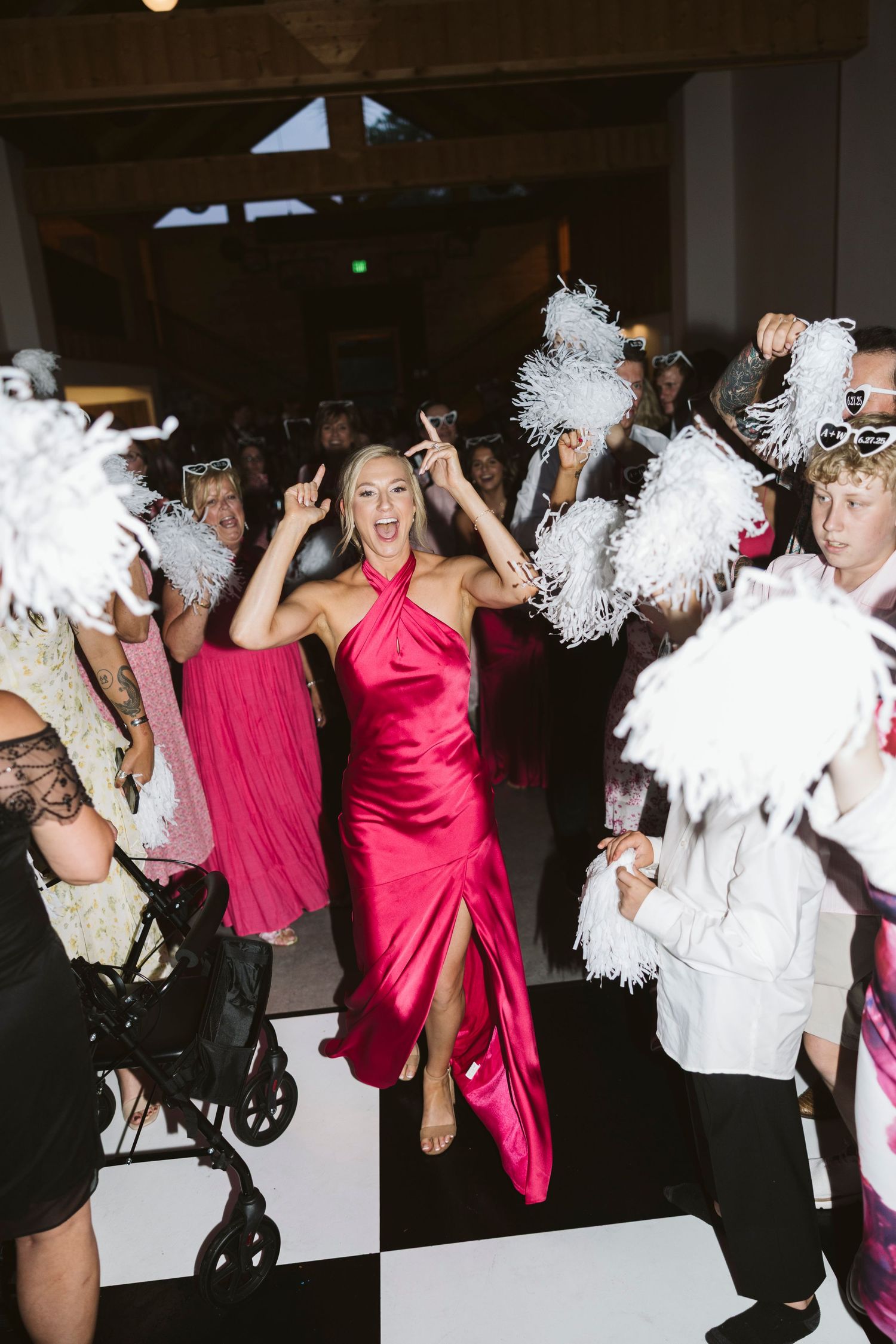 Wedding party dancing and celebrating with white pom poms at a reception.