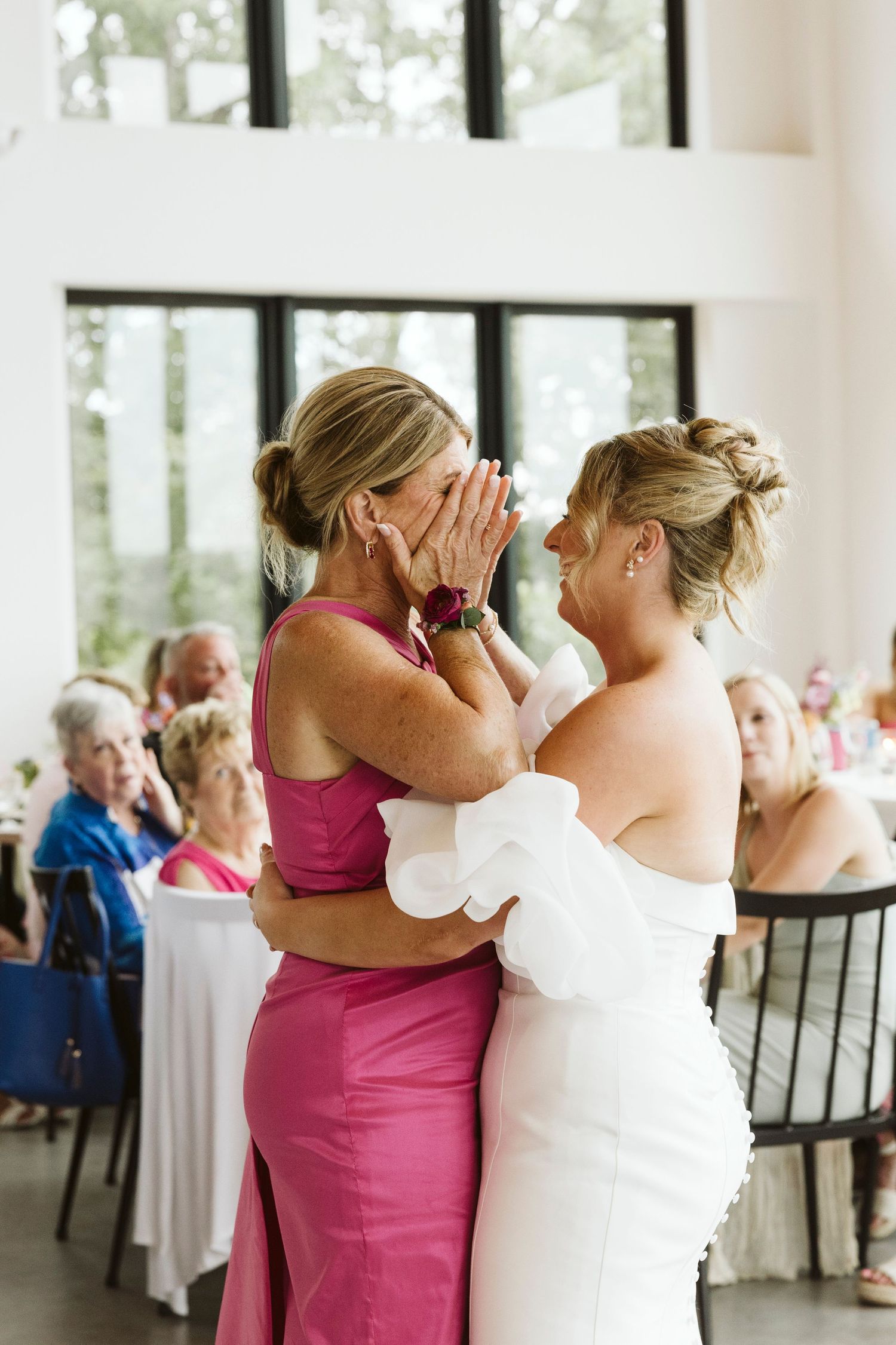 Emotional wedding reception moments captured in bright modern venue with white walls.