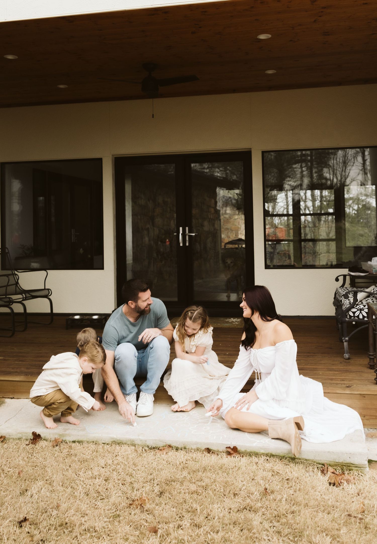 Family sitting together on blanket outside modern home.