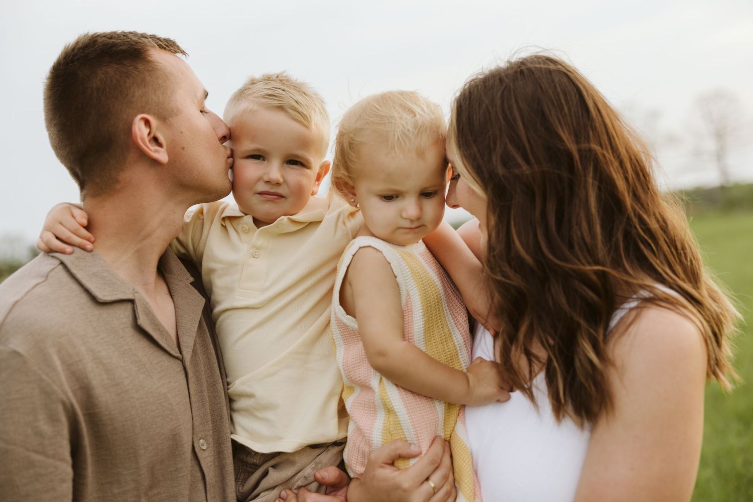 Family sharing a tender moment together outdoors in a natural setting during golden hour.