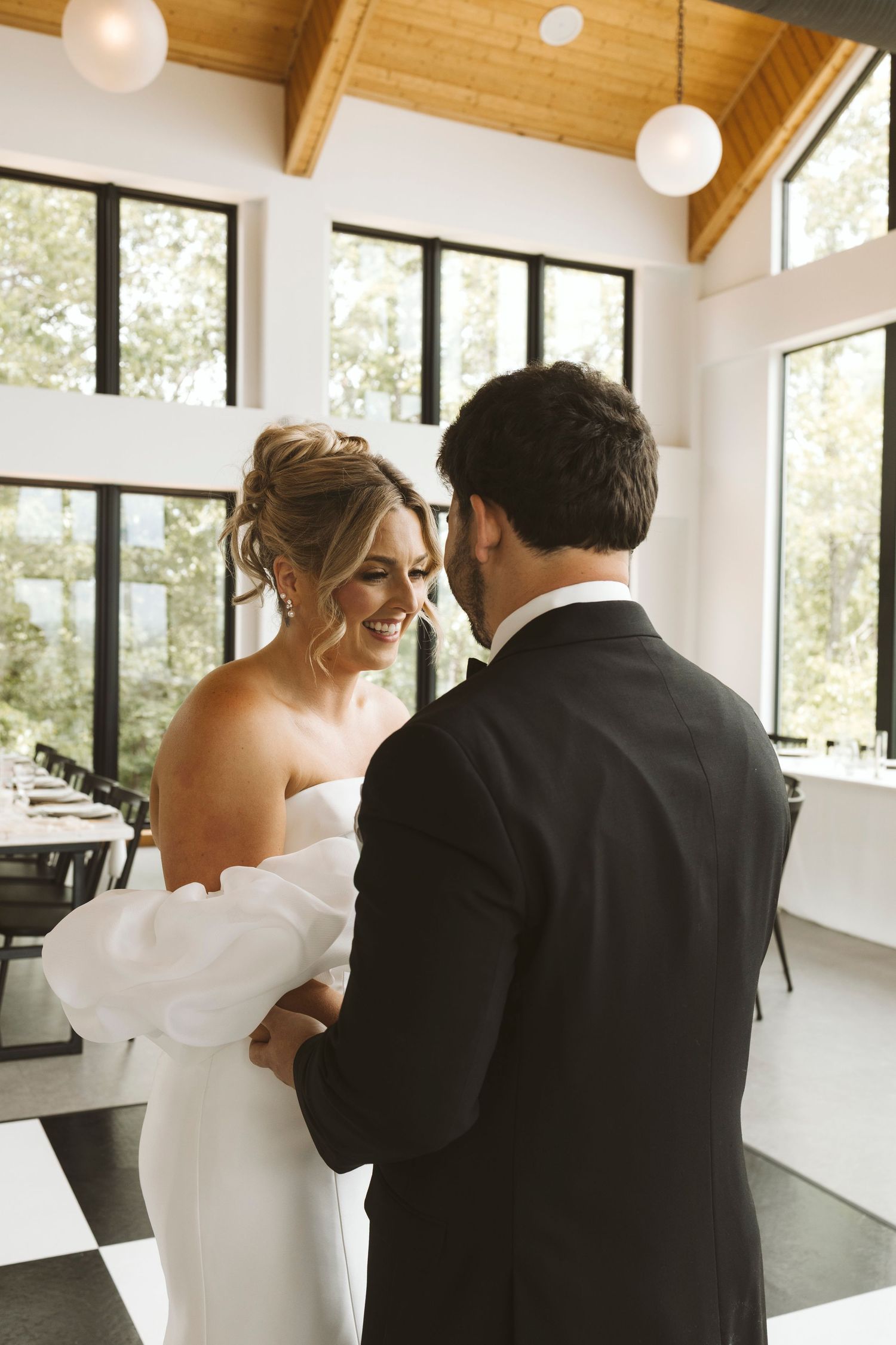 A tender moment shared in a bright modern venue with floor-to-ceiling windows.