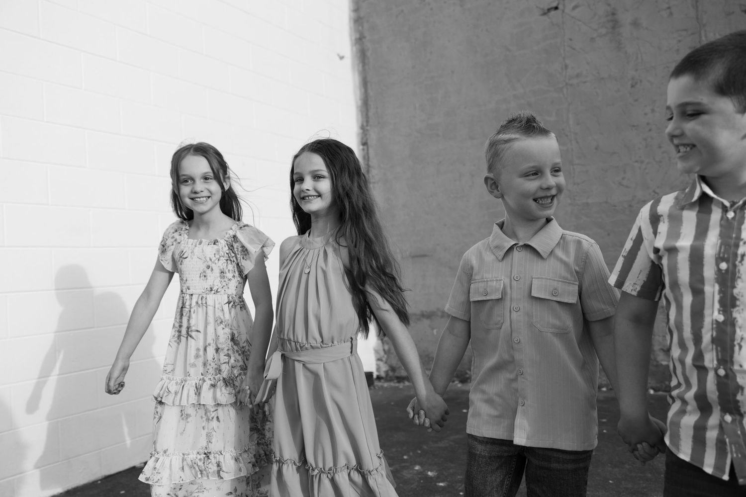 Children in casual attire standing together against a gray wall.