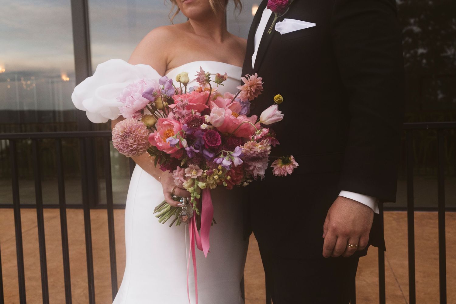 Elegant bridal portrait with stunning floral bouquet against modern architecture.