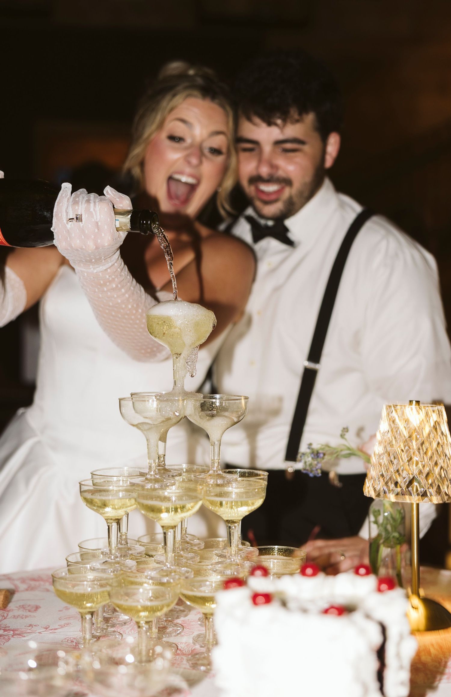 Champagne tower being poured at an elegant wedding reception with crystal glasses.