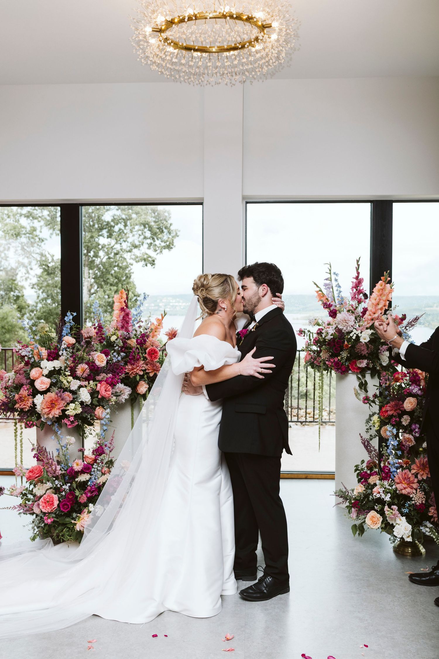 A wedding ceremony in a modern venue with stunning floral arrangements and a crystal chandelier.