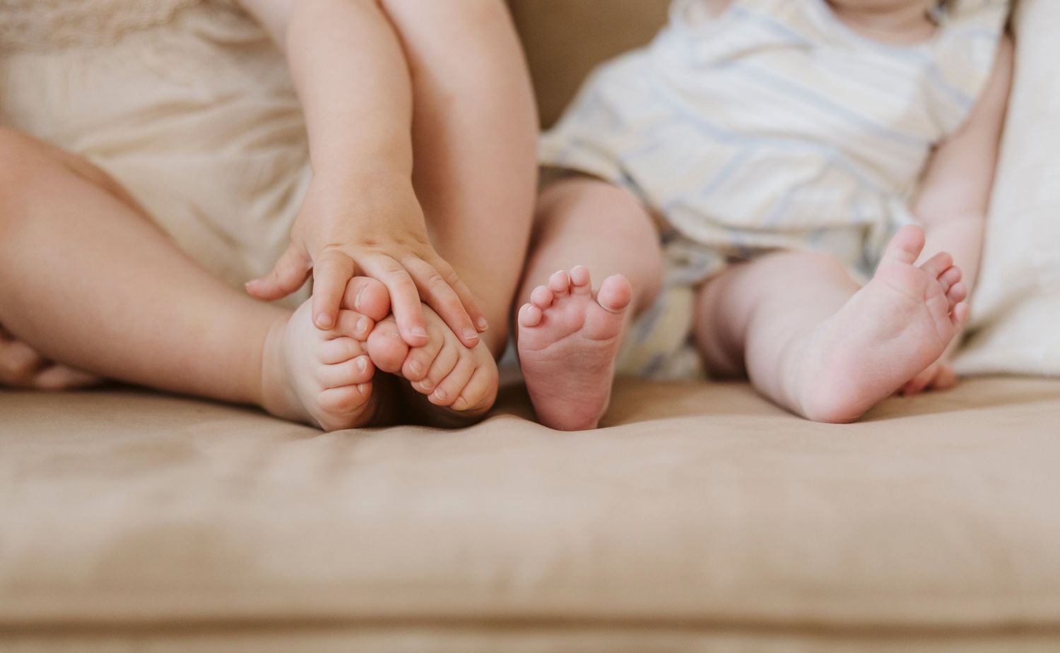A series of baby feet lined up next to each other on a neutral surface.