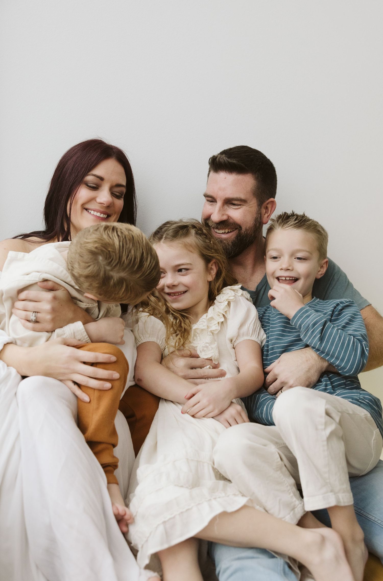 A joyful indoor family portrait showing genuine laughter and embraces.