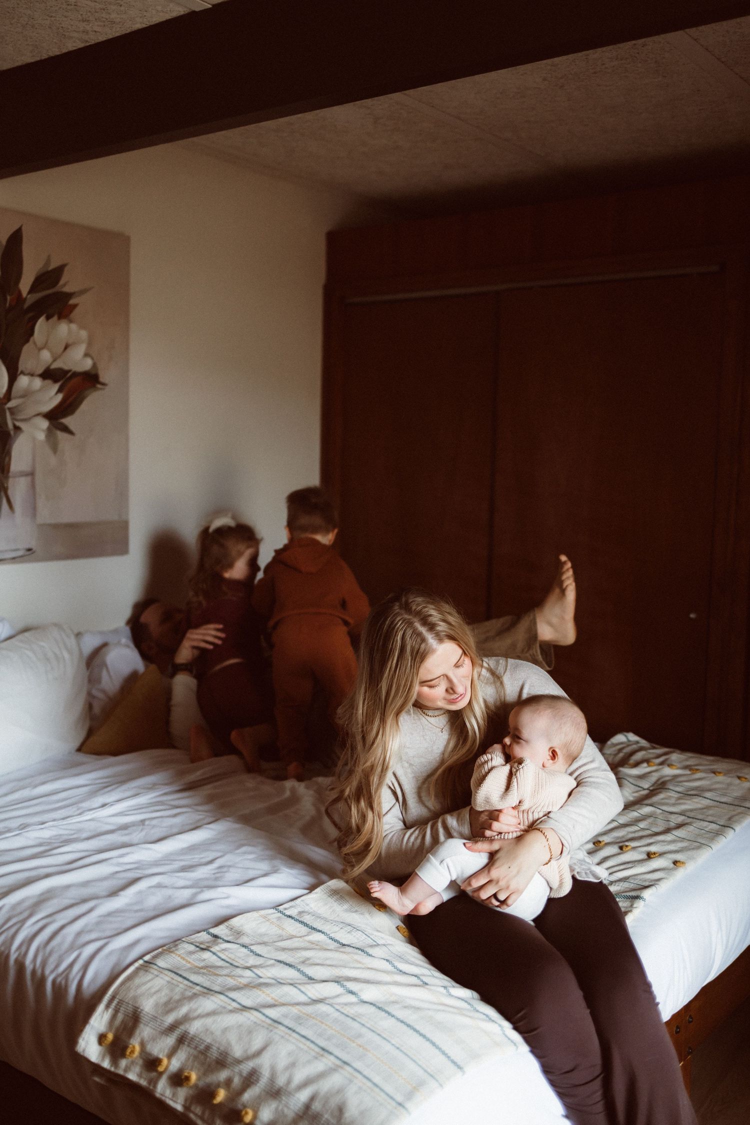 Family relaxing on bed with kids in matching brown outfits.