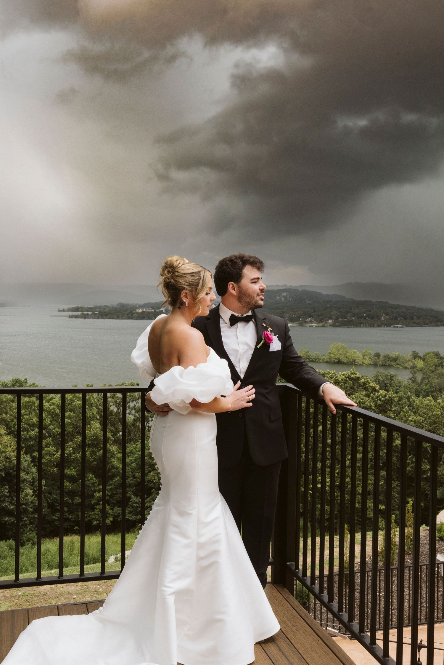 Dramatic wedding photos on a balcony overlooking mountains with stormy skies in the background.