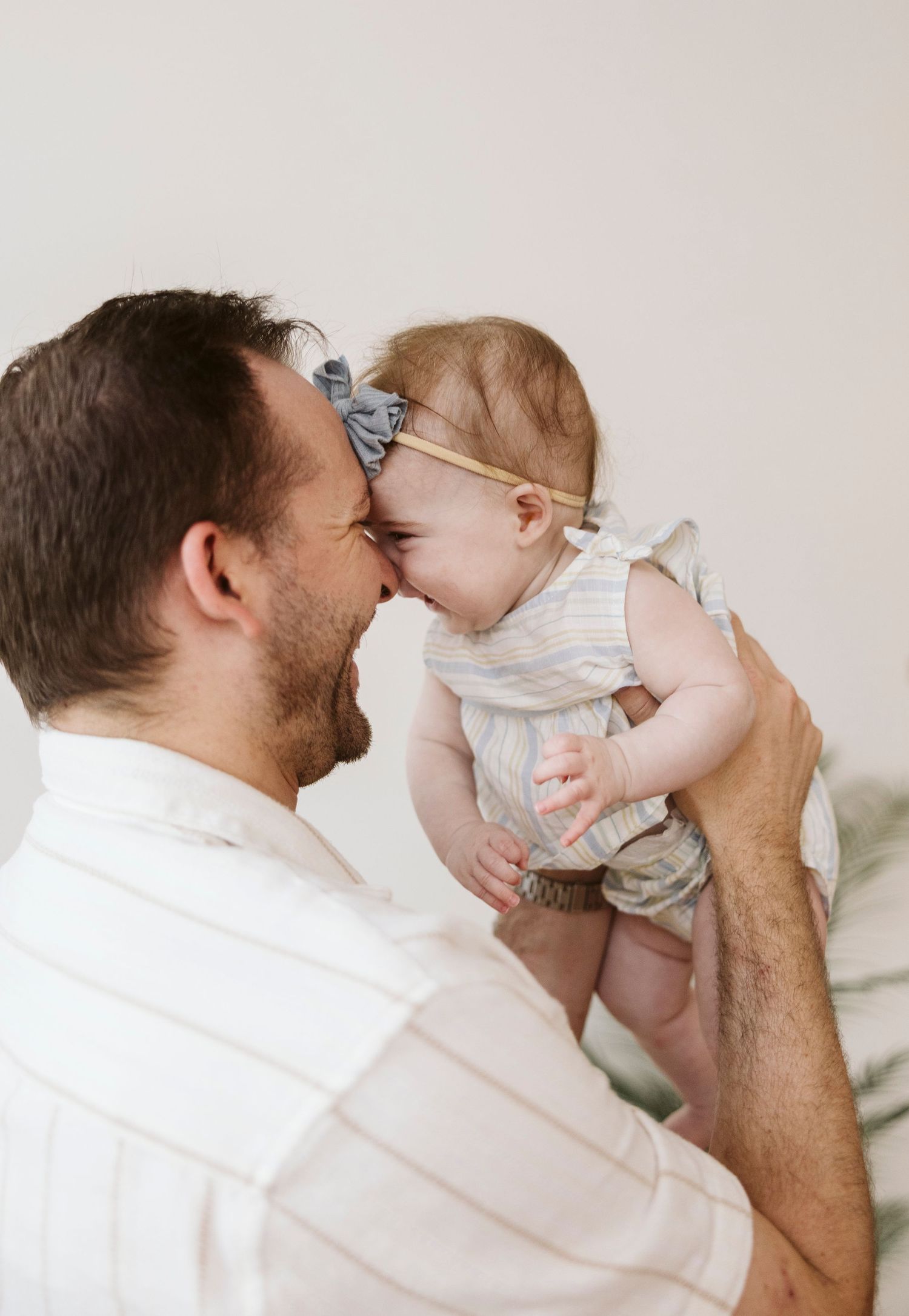 Playful interaction between parent and baby against white background.