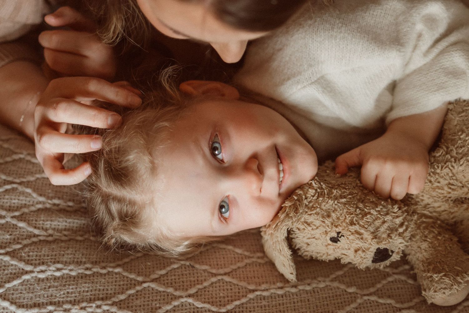 Close-up portrait on bed with stuffed bunny toy.