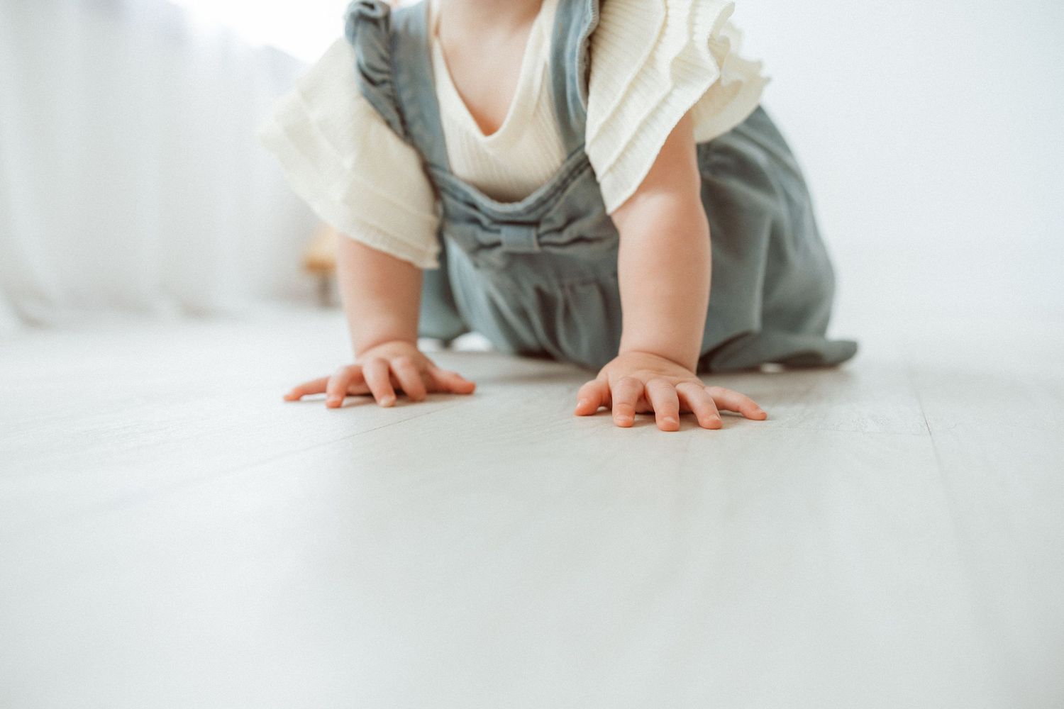 Close up of small hands on white floor while crawling.