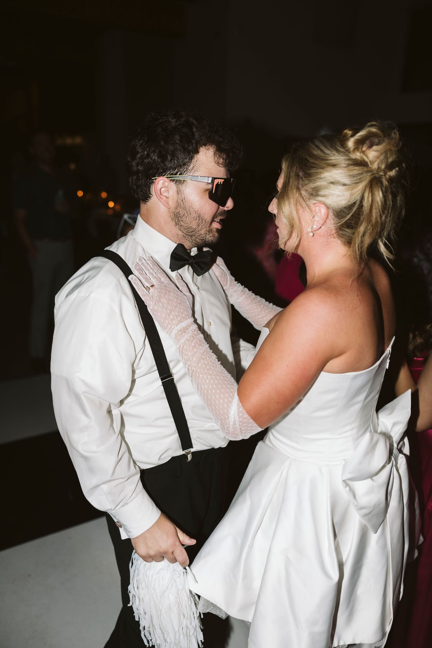 A couple shares an intimate dance moment at their wedding reception with the groom in suspenders.