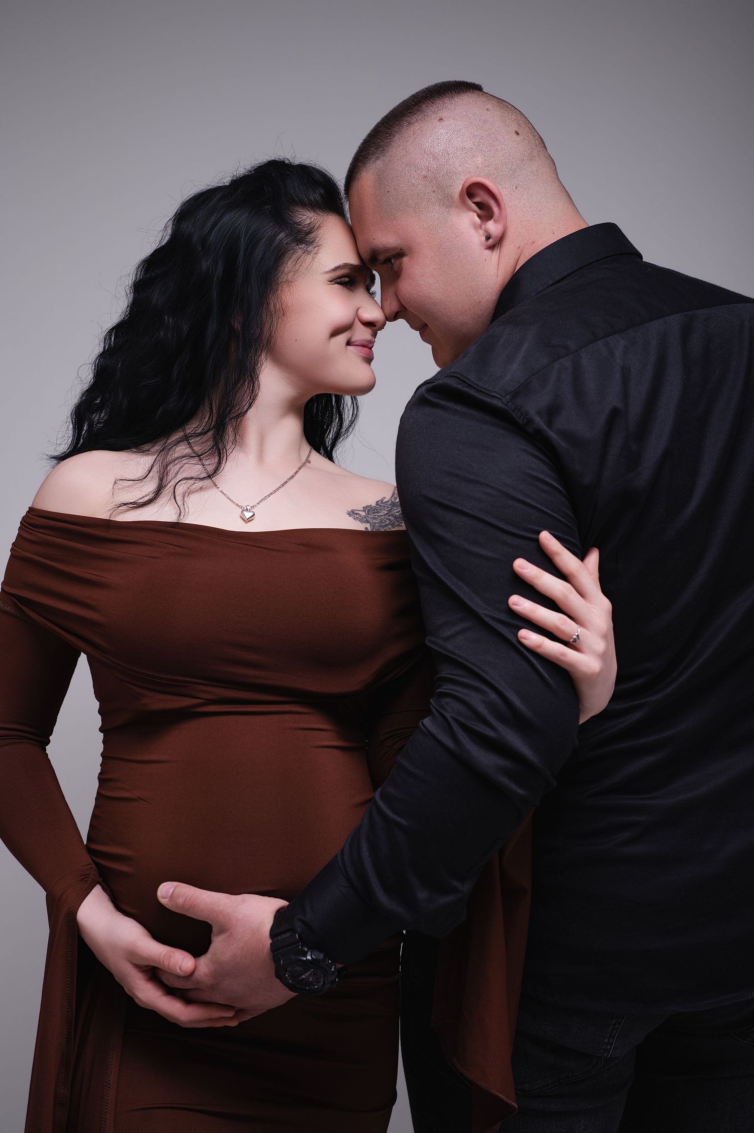 Elegáns páros kismama portré barna ruhában stúdióban