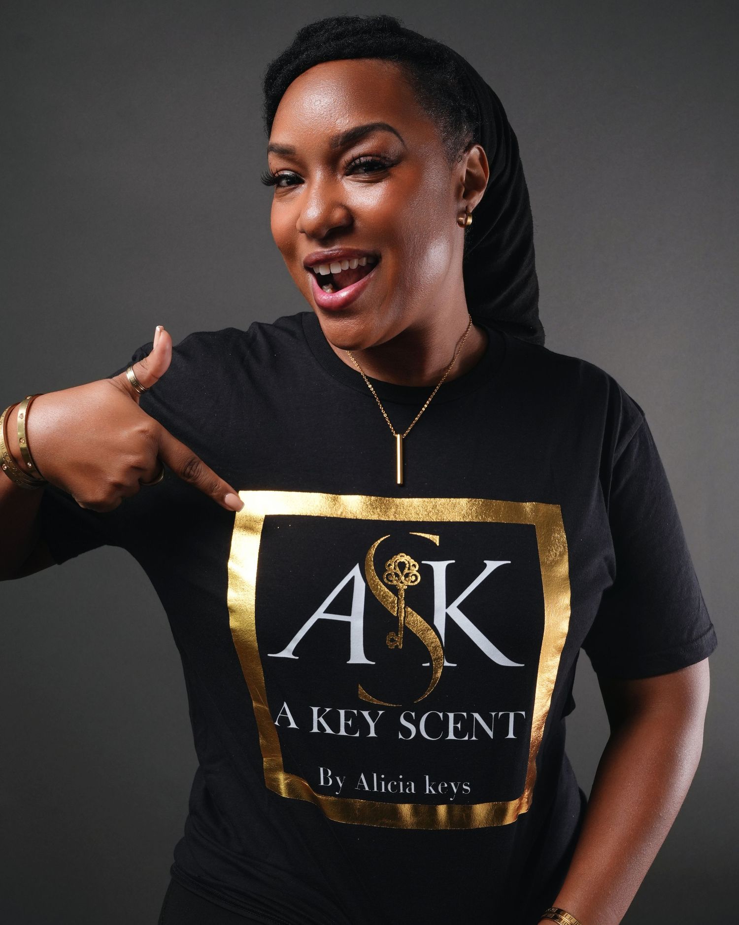 Brand promotional images showing A Key Scent logo design with gold accents on black clothing against dark backdrop.