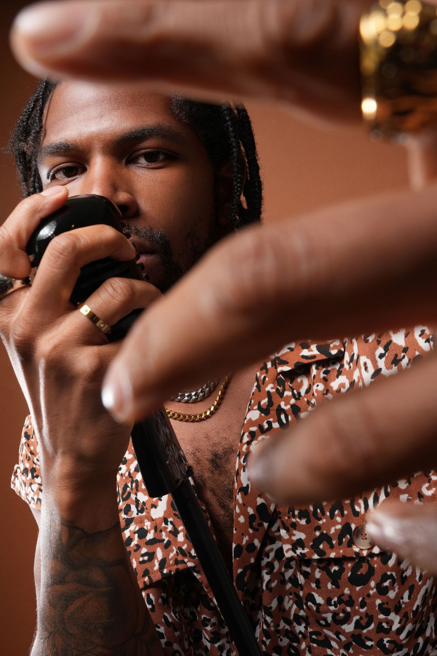 Artistic photo with microphone and animal print shirt showing hand gestures.