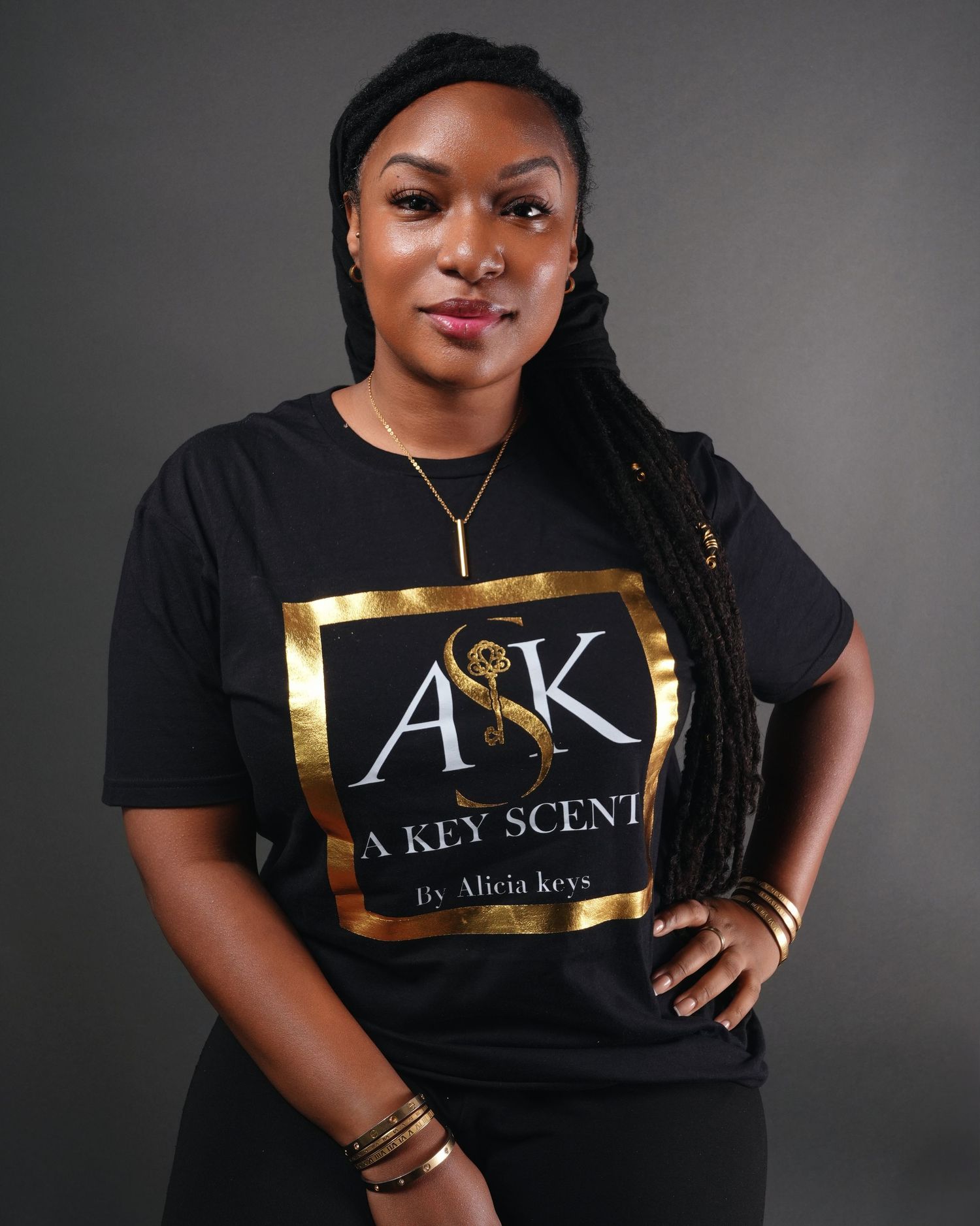 Professional studio portraits show a model in a black t-shirt with gold accents posing against a gray backdrop.