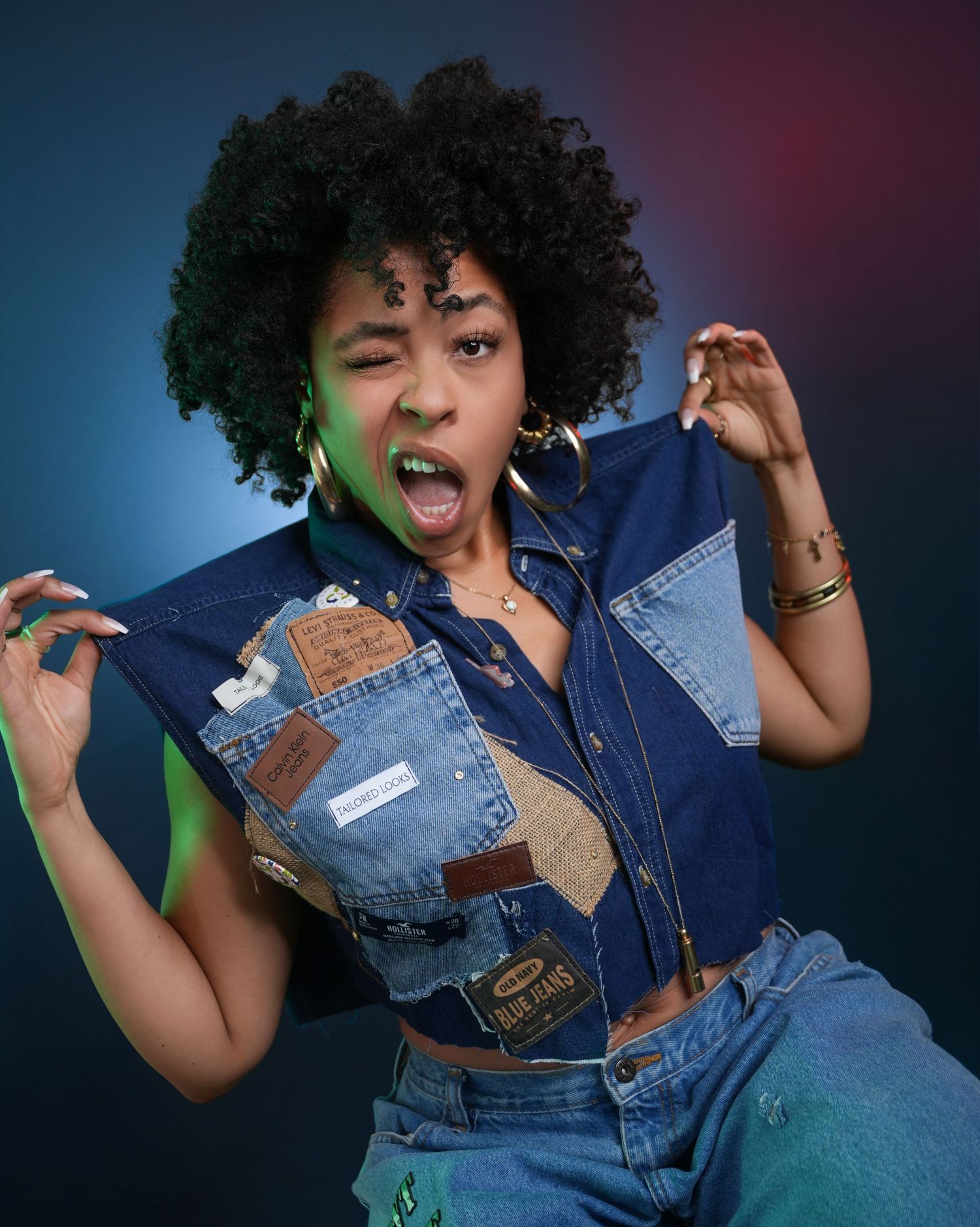 Energetic woman in denim dancing against colorful studio backdrop with dramatic lighting.