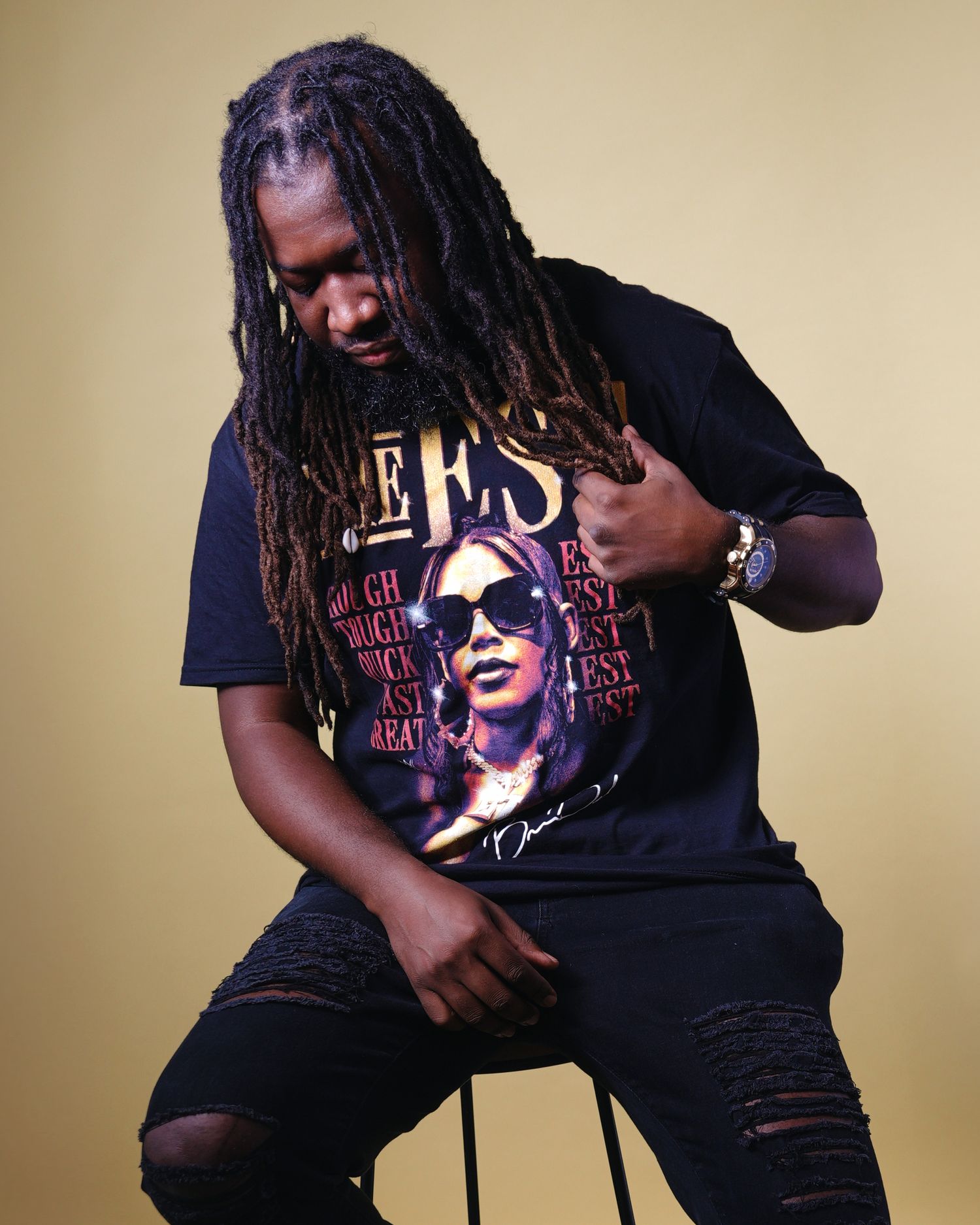 Person wearing Aaliyah graphic t-shirt poses thoughtfully against beige background.
