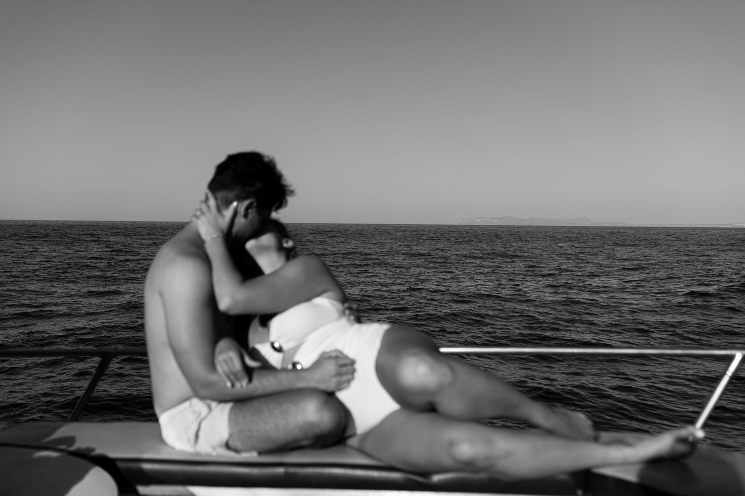 Couple lounging intimately on a boat deck with ocean views in black and white. Romantic couples photography in Greece.