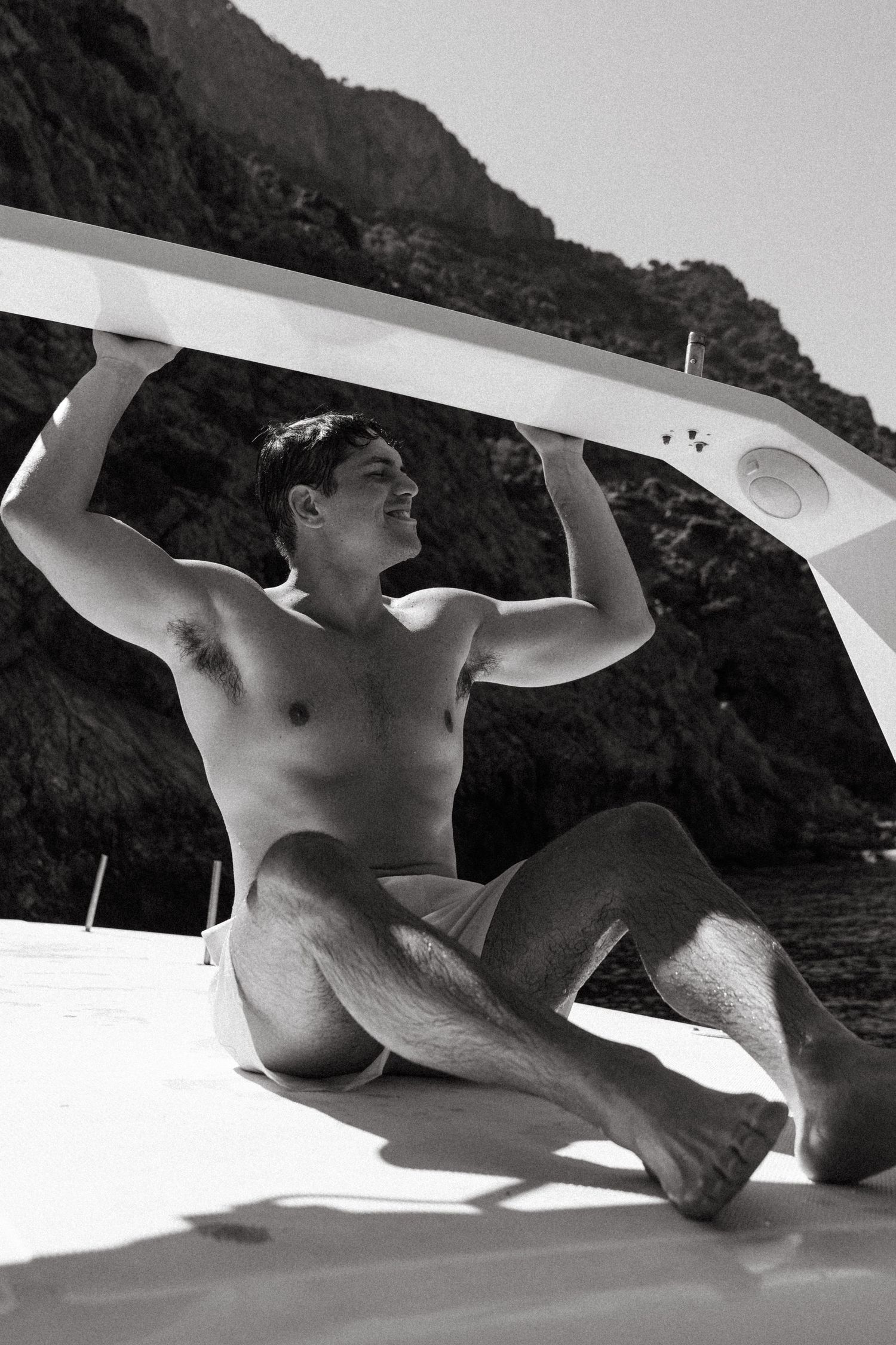 Artistic black and white photo of someone lounging on a white boat deck in Greece.